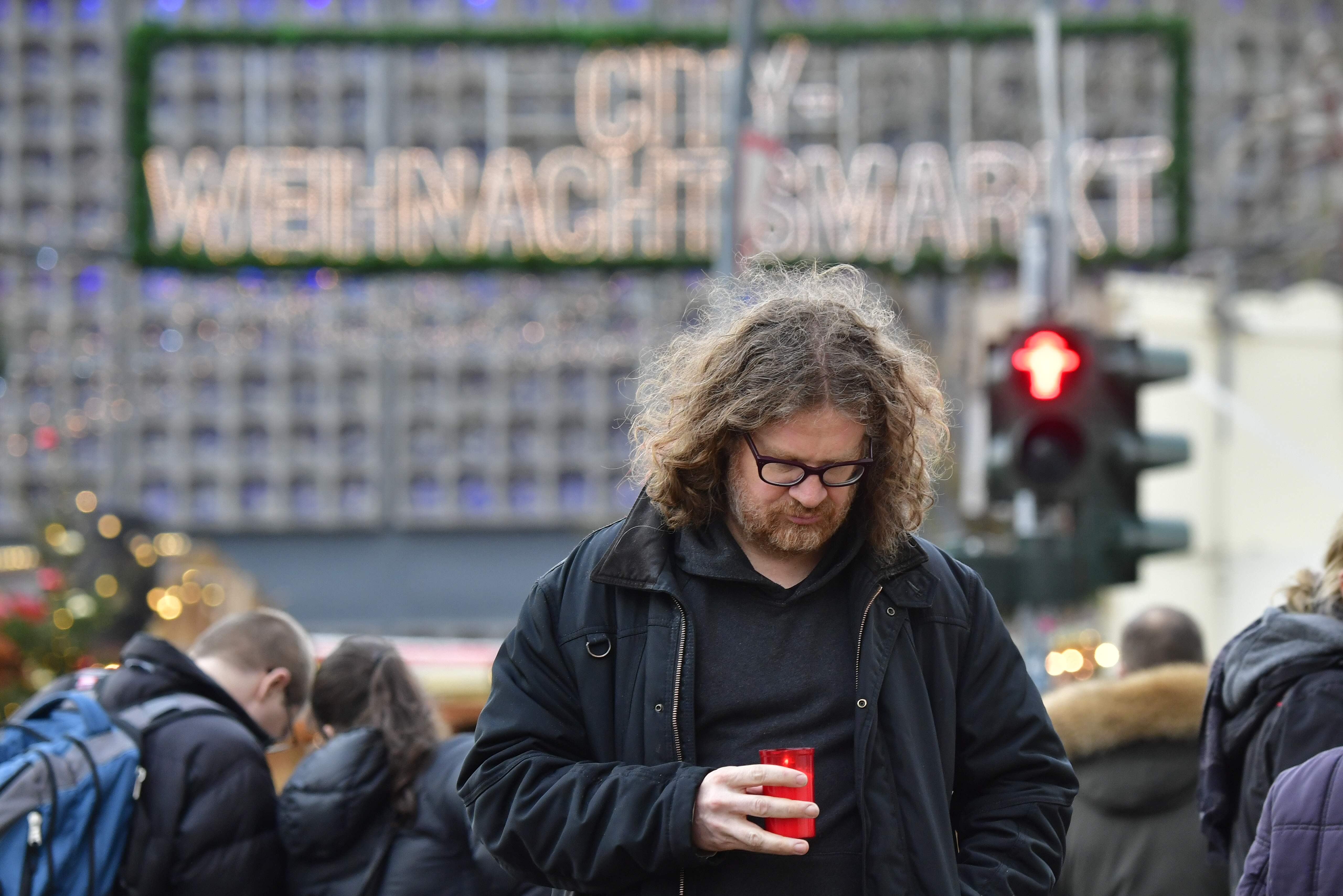 ألمانى يضع شمعة أرواح ضحايا حادث برلين، فى سوق عيد الميلاد قرب كنيسة قيصر ويلهلم التذكارية - أ ف ب