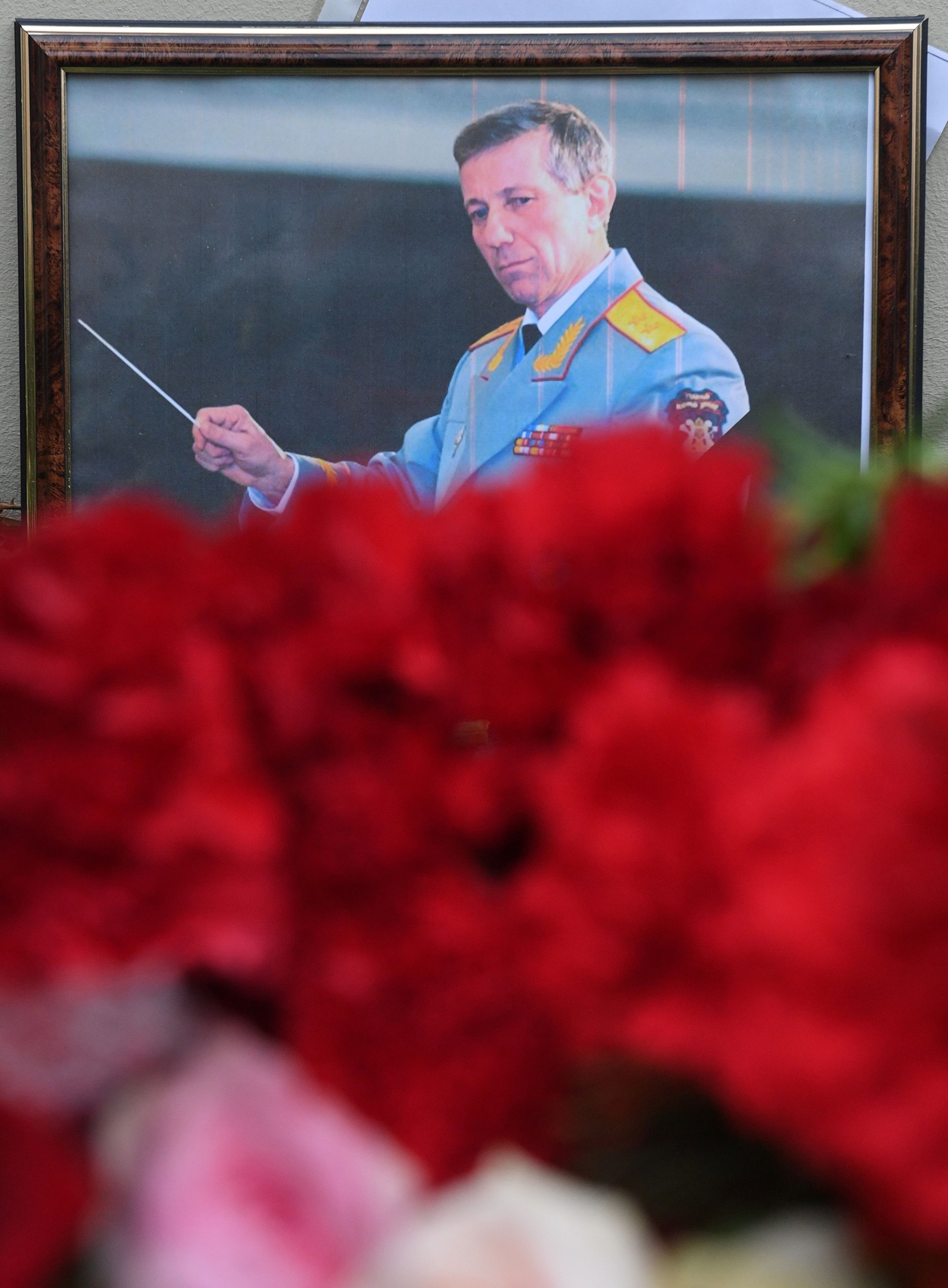 صورة رئيس فرقة اليكسندروف الروسية وسط باقة من الزهور تأبينا لروحه على باب مسرح الفرقة