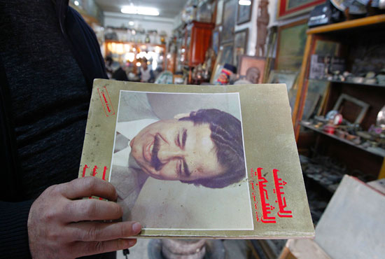 عراقى يمسك بكتاب يحمل صورة لصدام حسين فى العاصمة بغداد