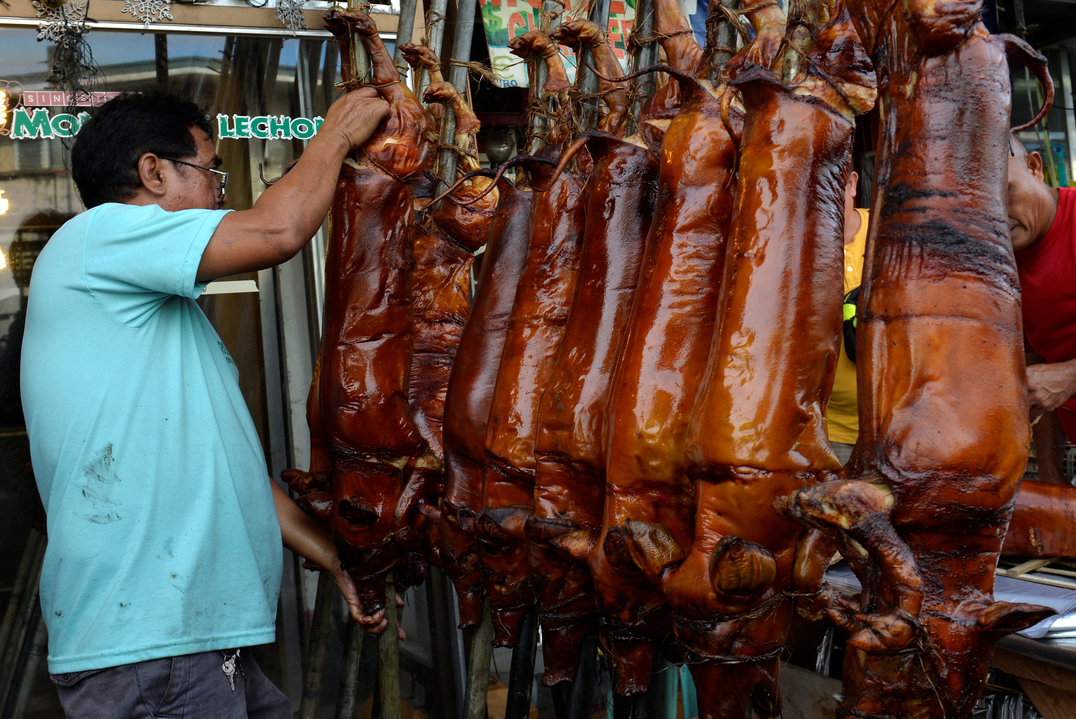 فلبينى يعلق لحوم خنزير فى أحد المتاجر فى مانيلا للاحتفال 2 - رويترز