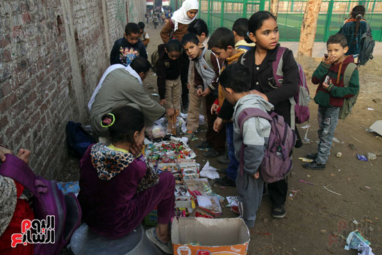 الطلاب يشترون الحلويات من الباعة قبل دخول المدرسة