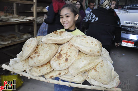 طفلة تحصل على الخبز المجانى من مخبز محمد عوف