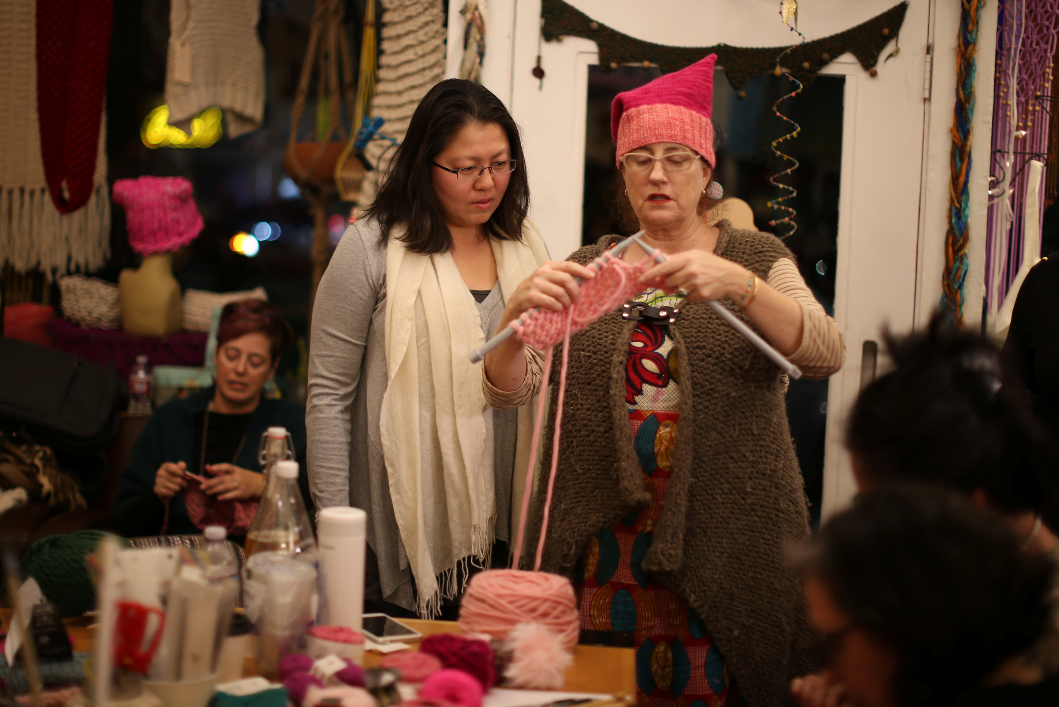 سيدة توضح لأحدى المشاركات كيفية صناعة القبعات الوردية بالتريكوه