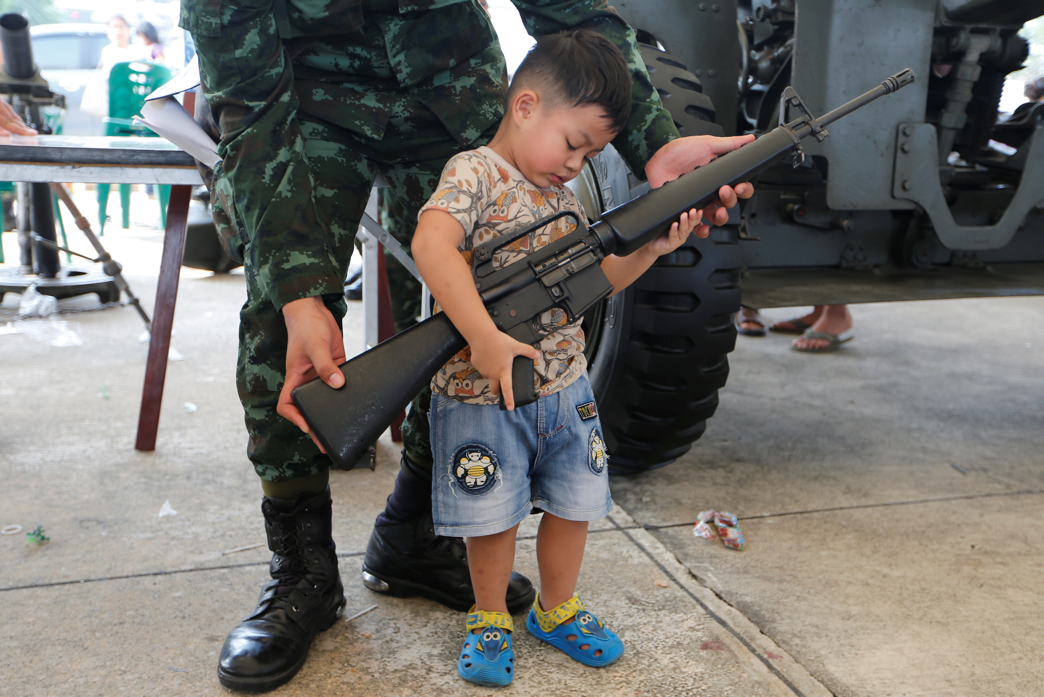 طفل يمسك بسلاح آلى خلال احتفالات يوم الطفل فى تايلاند