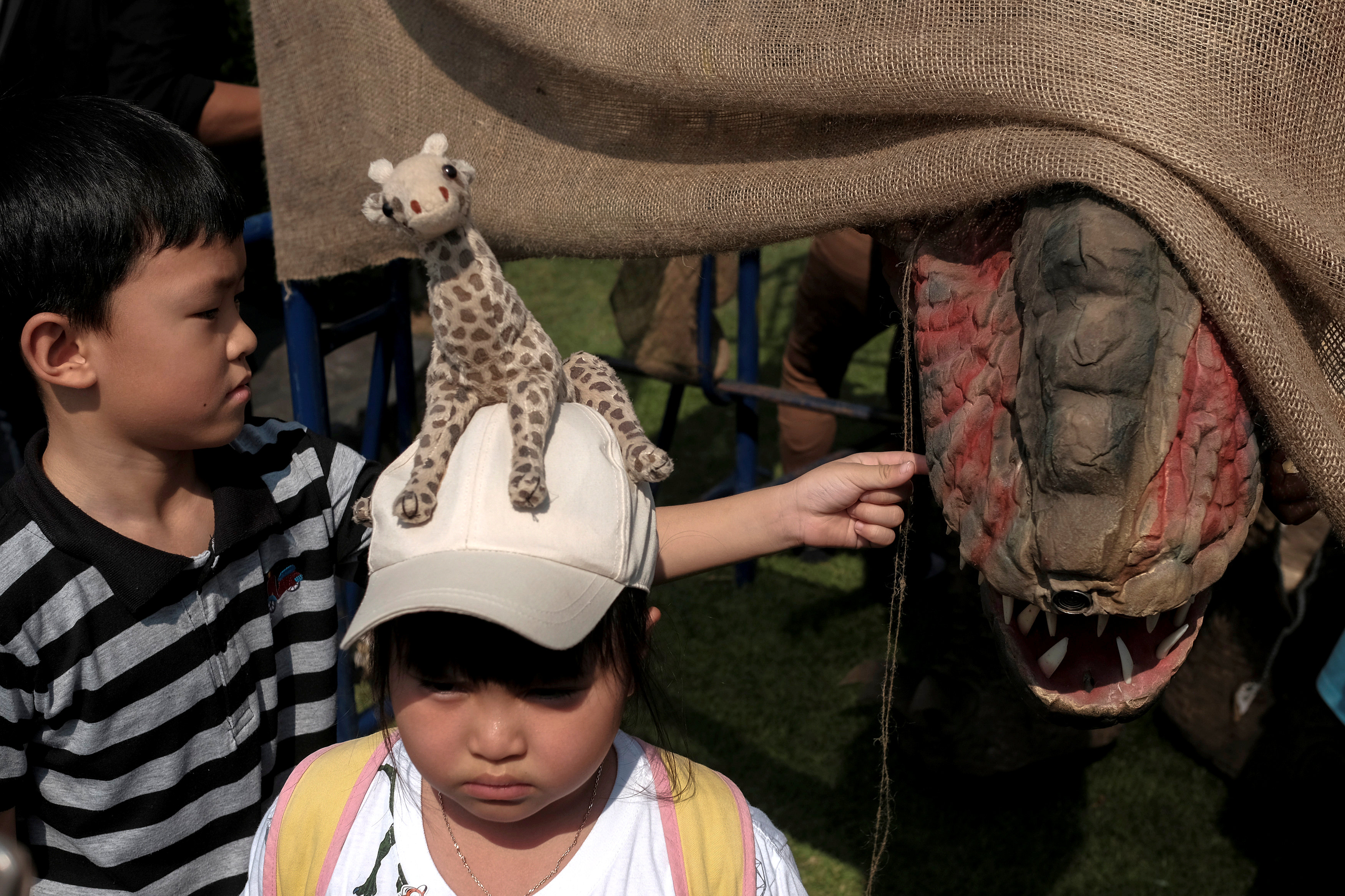طفل يلتقط صورة وعلى رأسه دمية زرافة خلال الاحتفال بيوم الطفل فى تايلاند