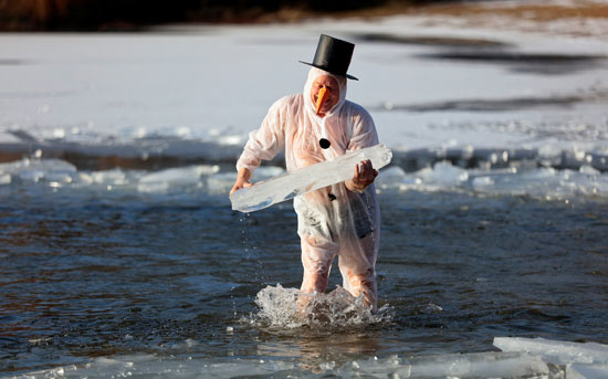 رجل يحمل لوح ثلج فى البحيرة الجليدية خلال احتفالات كرنفال السباحة بألمانيا