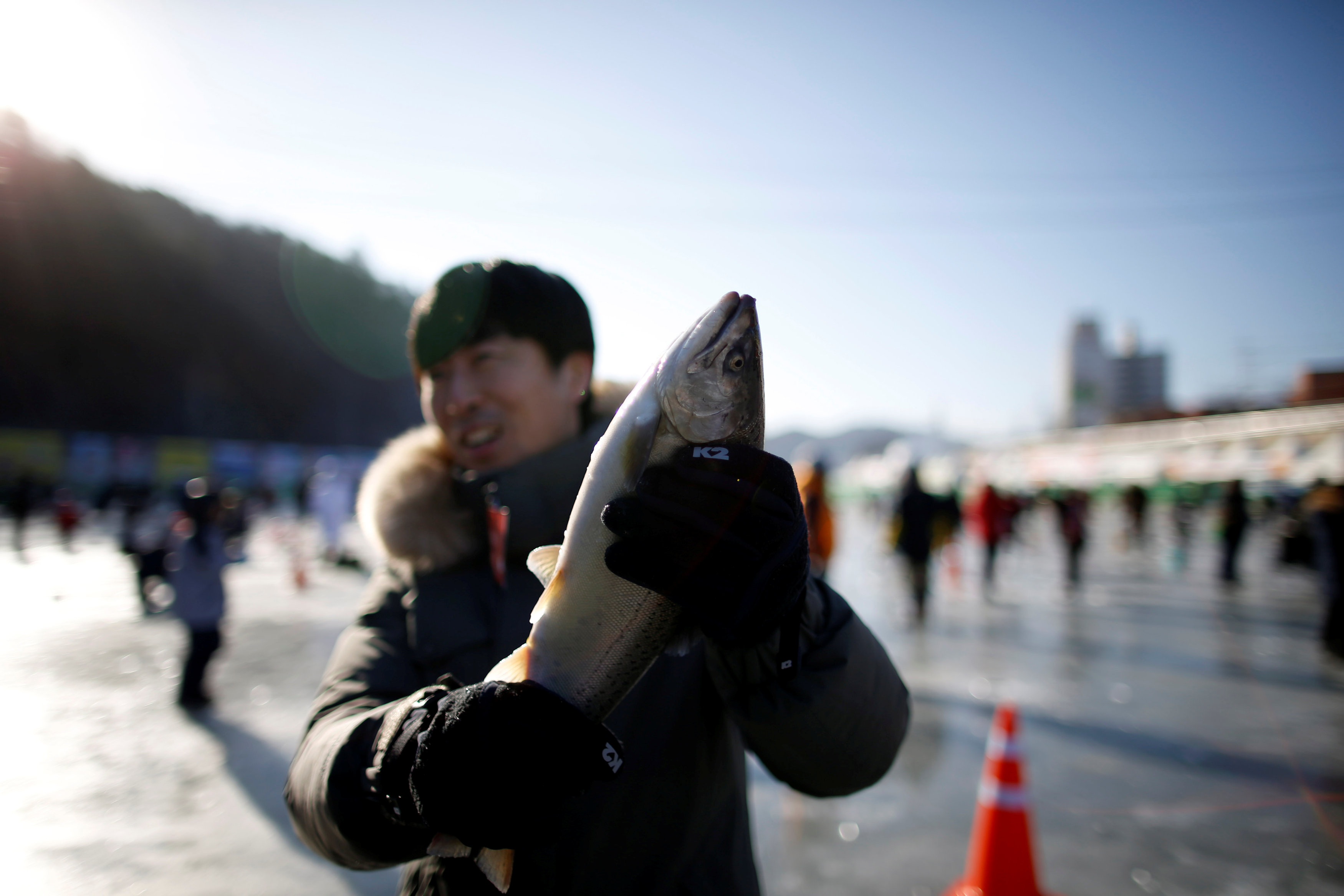 شاب يحمل سمكة بعد اصطيادها فى مهرجان الجليد بكوريا الجنوبية