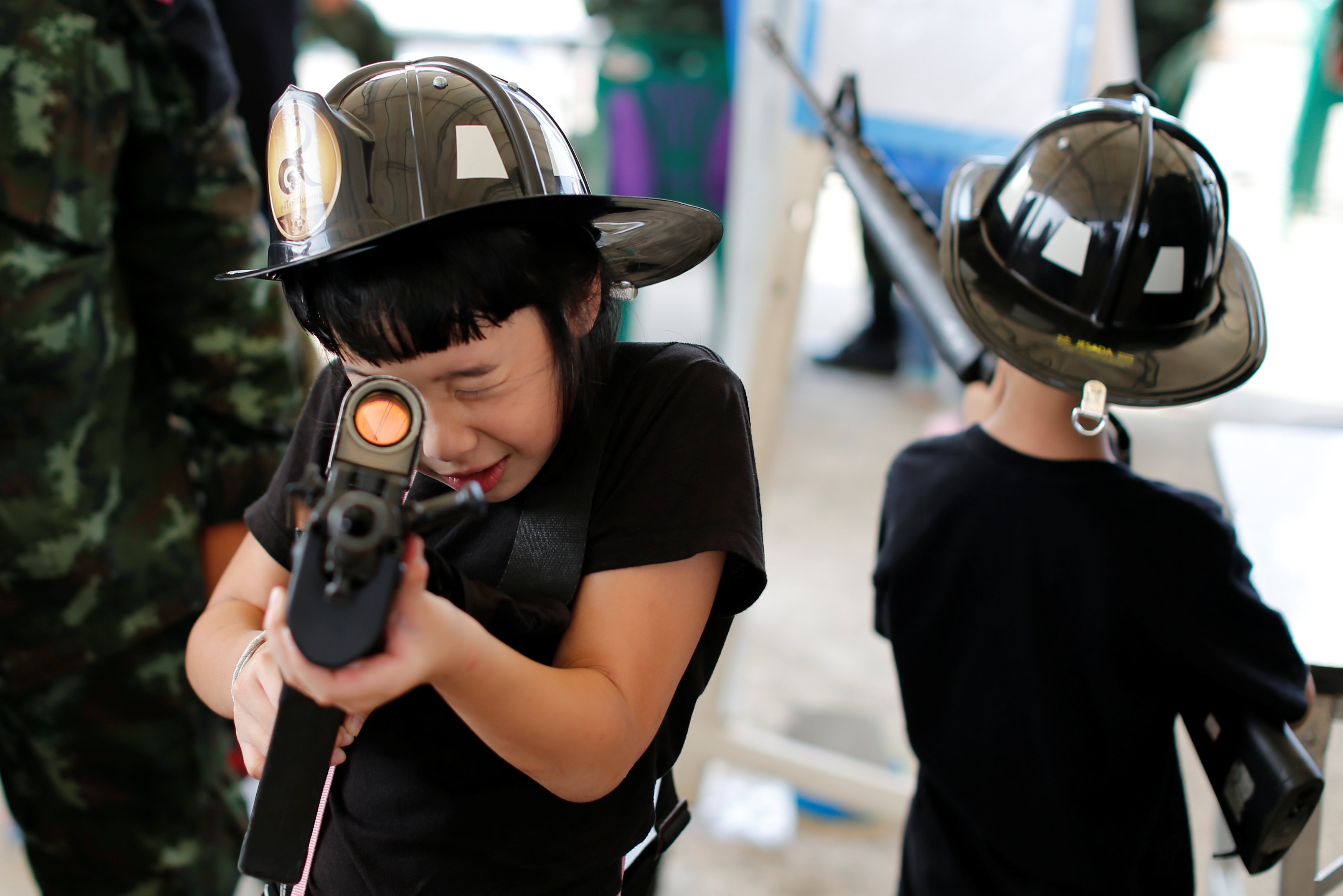 الأطفال يلعبون بالأسلحة الآلية خلال احتفالات يوم الطفل فى مقر حكومة تايلاند