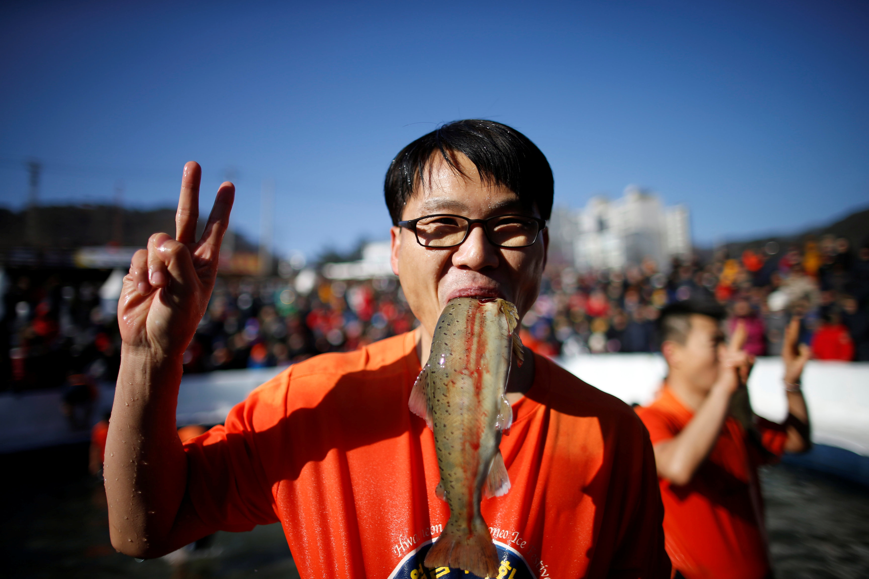 رجل يضع سمكة فى فمه خلال فعاليات مهرجان الجليد بكوريا الجنوبية