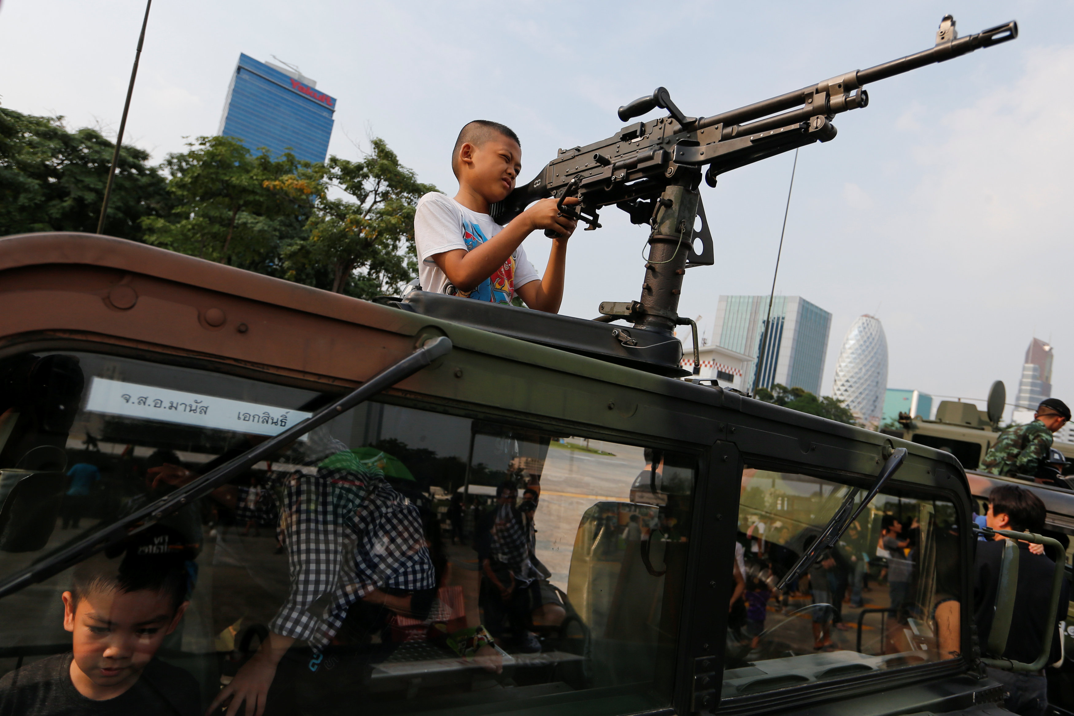 طفل يمسك بسلاح أعلى مدرعة فى مقر حكومة تايلاند خلال احتفالات يوم الطفل