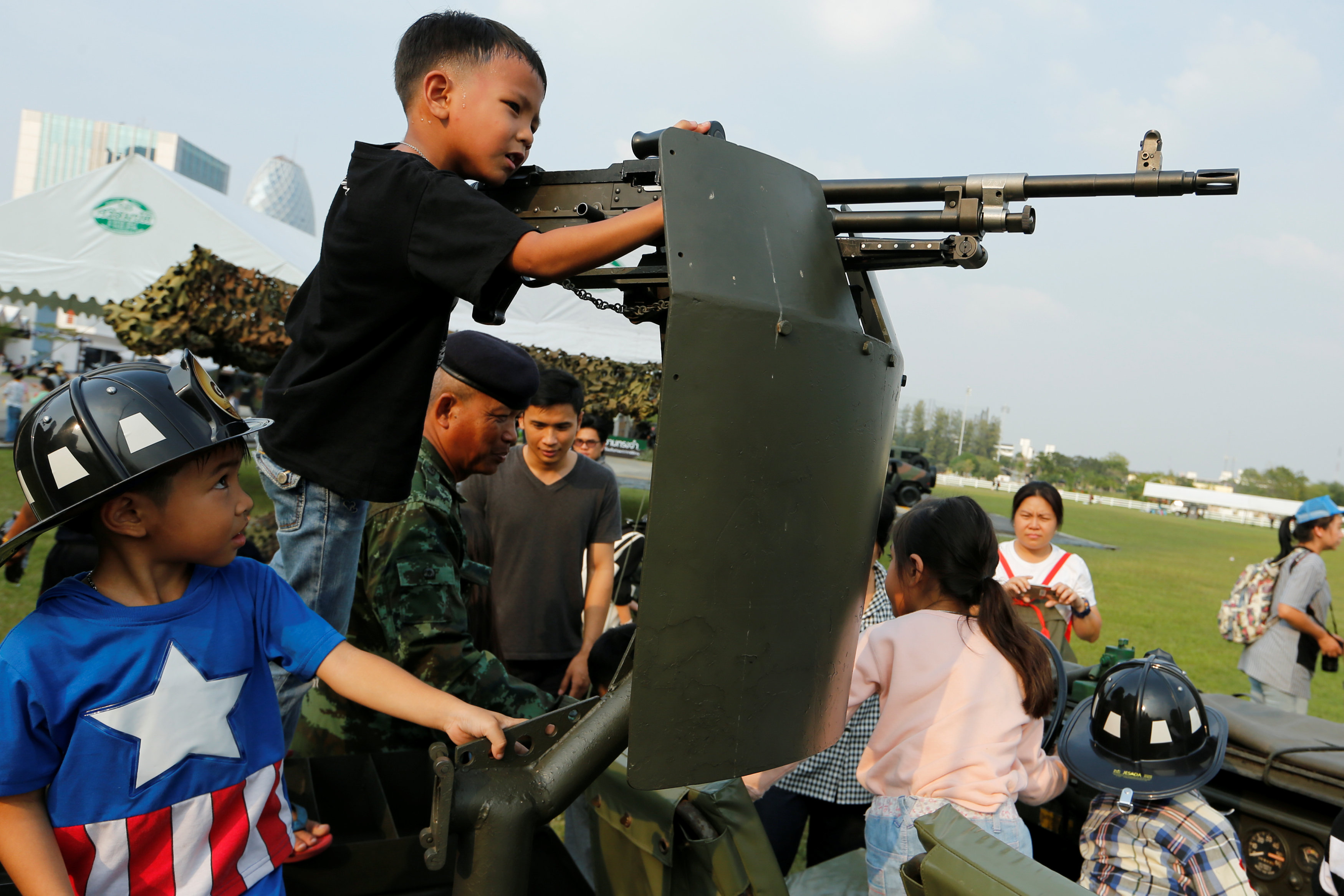 طفل يمسك بسلاح آلى أعلى مصفحة فى مقر الحكومة التايلاندية خلال احتفالات يوم الطفل
