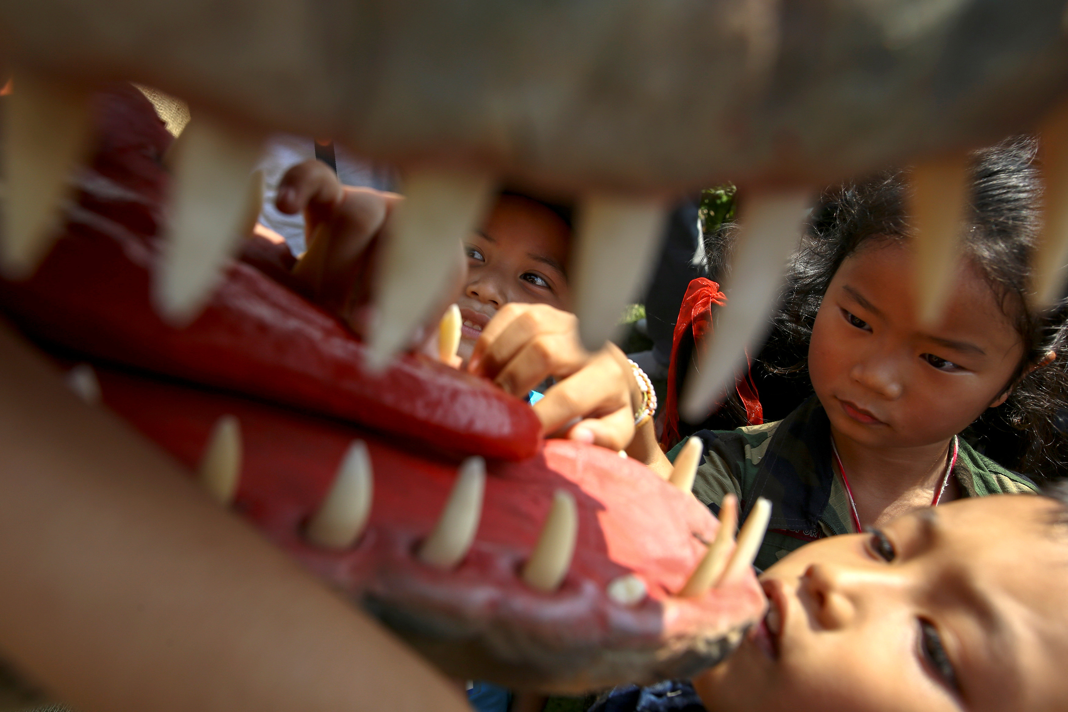 طفل يلهو مع تمثال دنياصور خلال احتفالات يوم الطفل فى تايلاند
