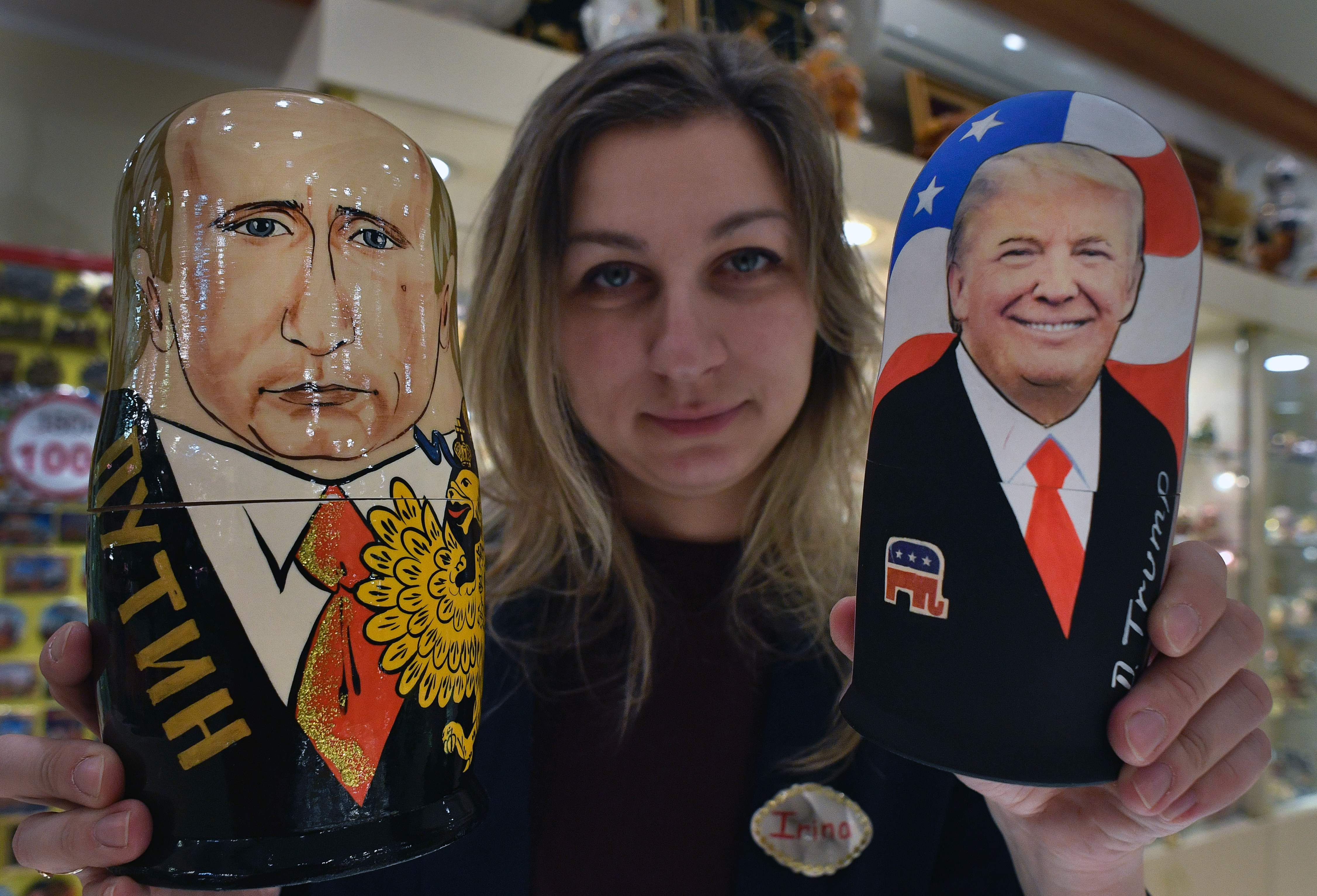 موظفة بمحل هدايا فى روسيا تحمل دمى خشبية مرسوم عليها صور بوتين وترامب