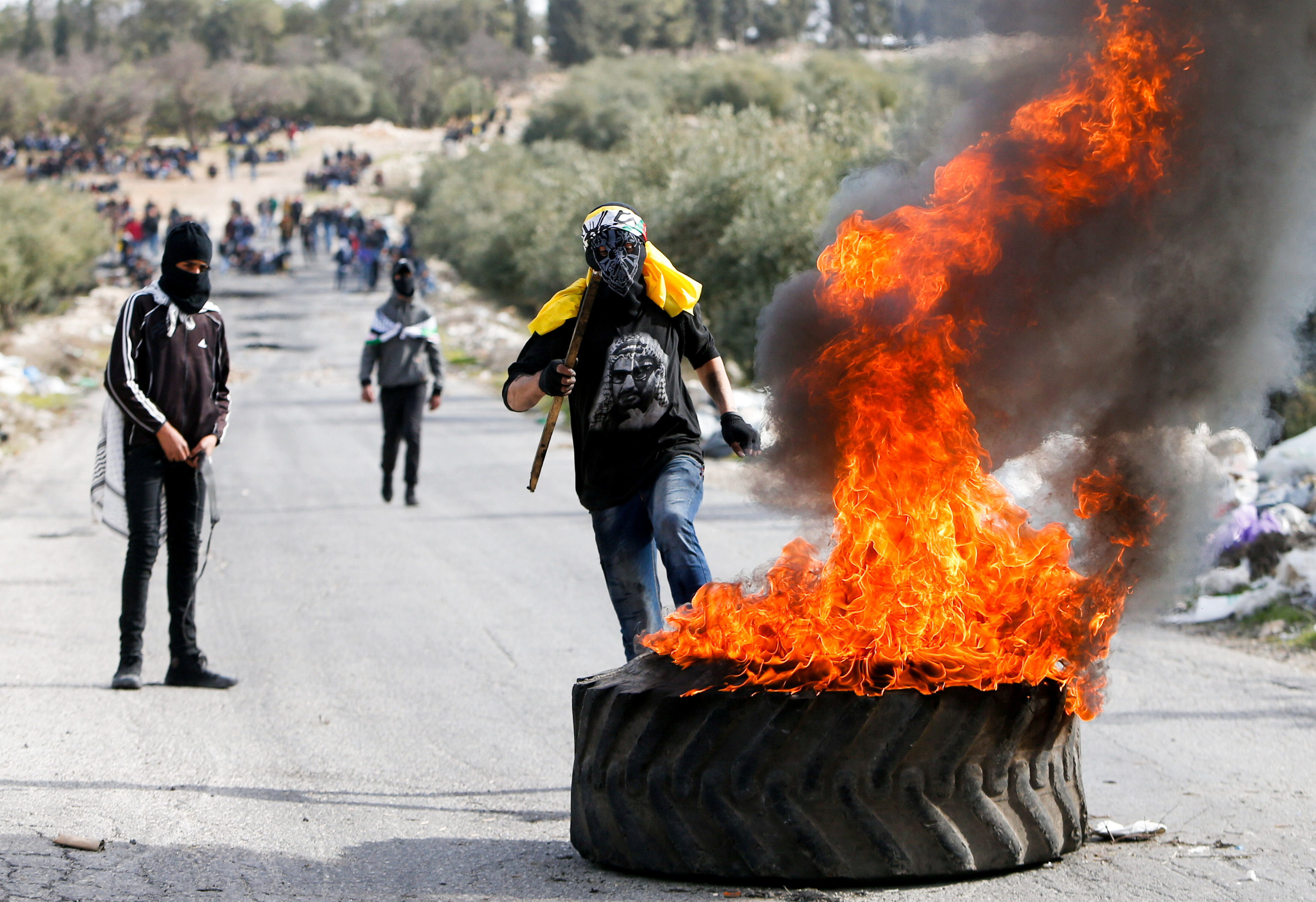 شباب فلسطينيون يشعلون النيران فى طارات خلال تشييع الجثمان - رويترز