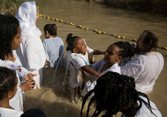 مسيحيون يعمدون أبناءهم فى نهر الأردن فى عيد الغطاس