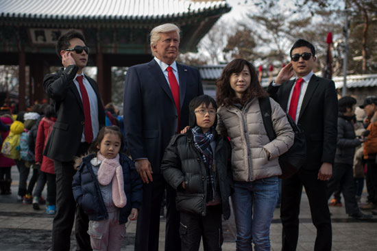 سيدة وأطفالها يتلقطون صور مع تمثال الشمع لدونالد ترامب فى سيول