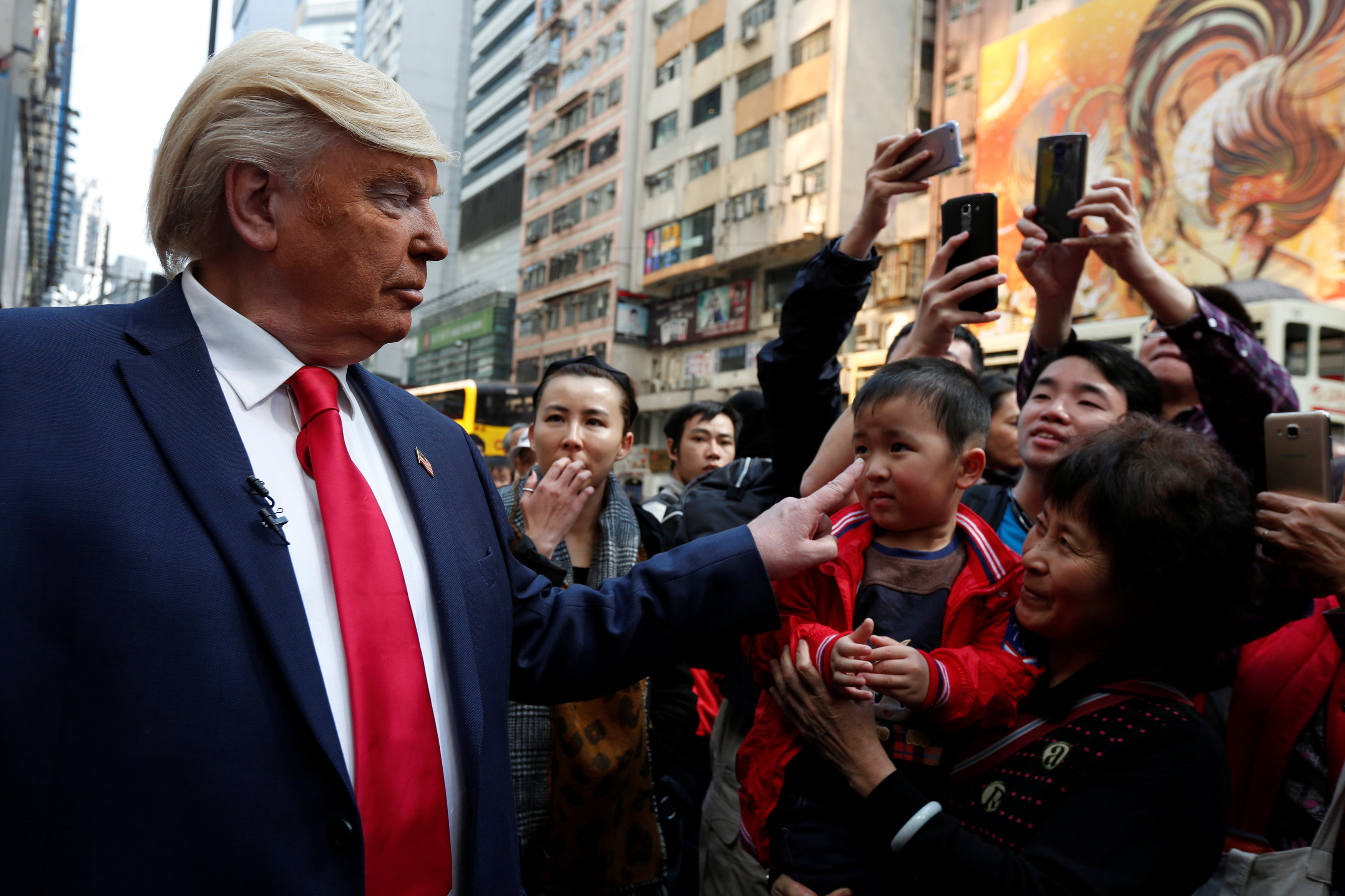 	شبيه دونالد ترامب يداعب طفل فى شوارع هونج كونج