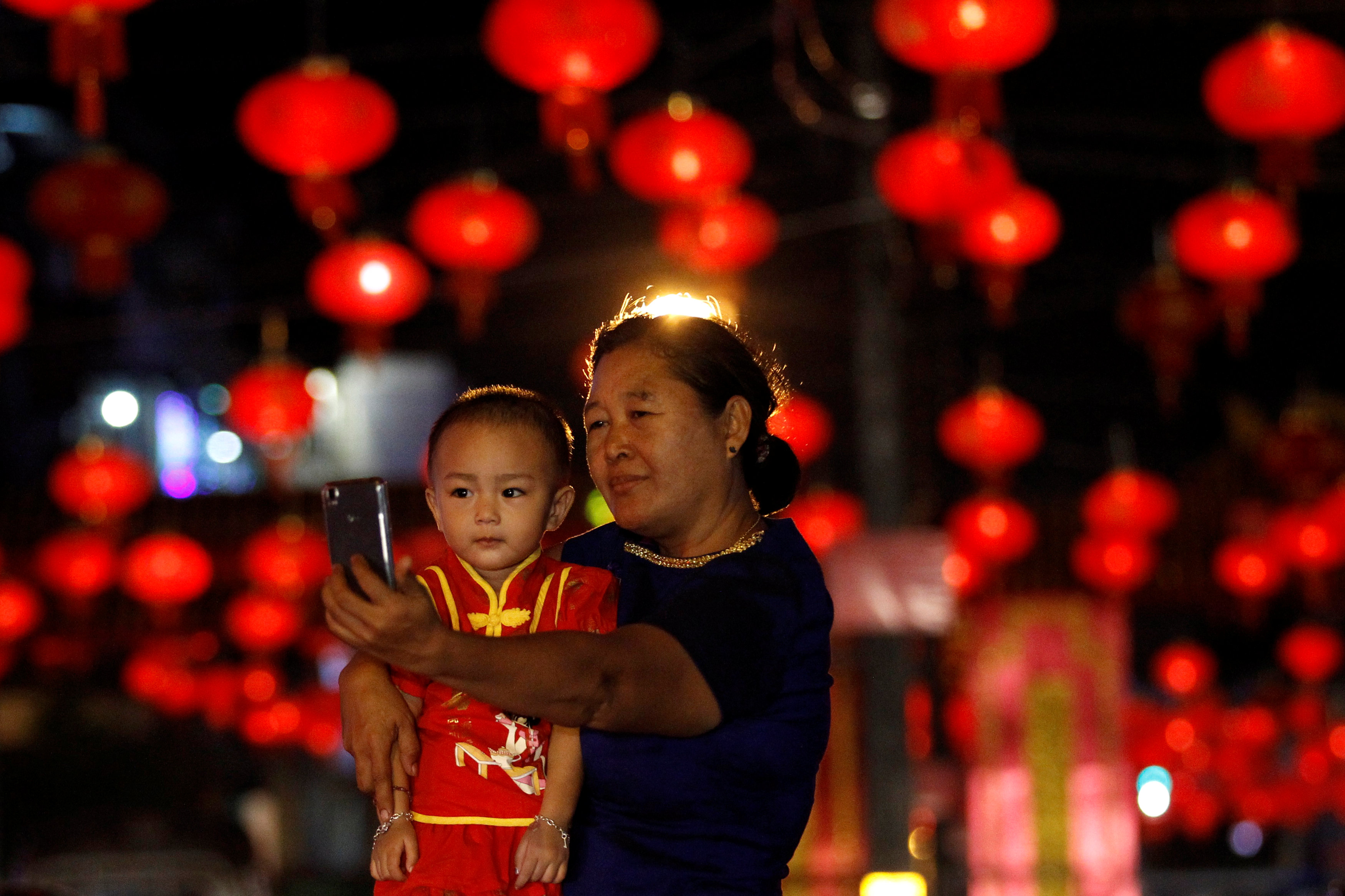 سيدة تلتقط صورة مع طفل خلال الاحتفال بالسنة الصينية الجديدة