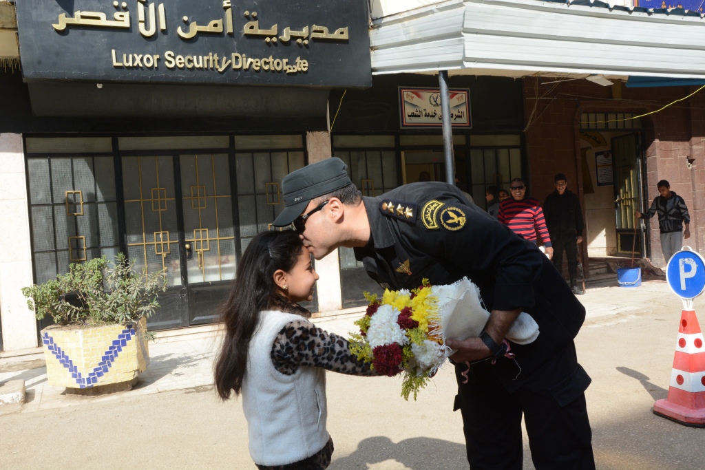 5- ضابط يقبل رأس طفلة خلال توزيعها الورود بالأقصر