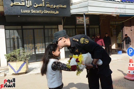 ضابط يقبل رأس طفلة خلال توزيعها الورود بالأقصر
