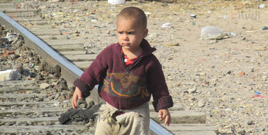 طفل ونظرة شاردة أثناء سيره على قضبان السكة الحديد