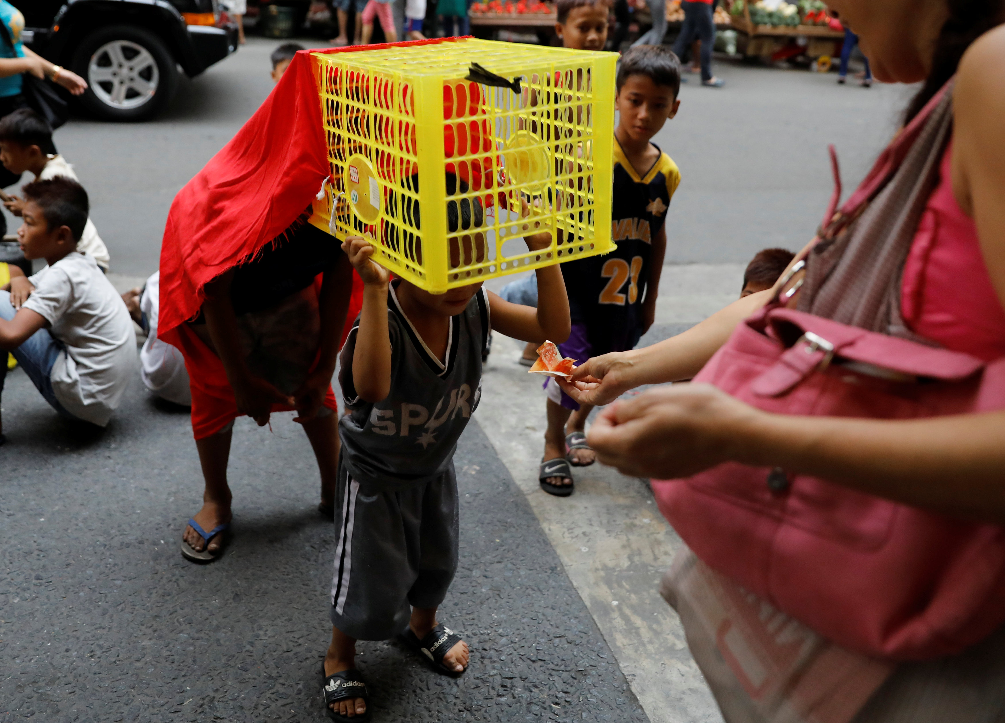 سيدة تعطى نقودًا لطفل فى الفلبين خلال رقصه فى الشارع بمناسبة السنة الصينية الجديدة