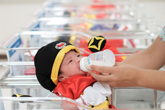 	طفل يتناول الحليب بعد ارتدائه ملابس احتفالات السنة الصينية الجديدة