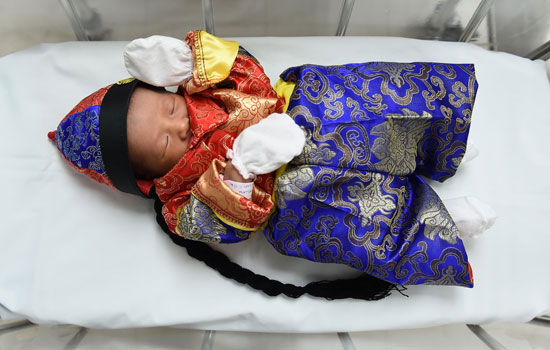 	طفل حديث الولادة فى تايلاند يرتدى زى مستوحى من الفنون الصينية احتفالًا بالسنة الجديدة