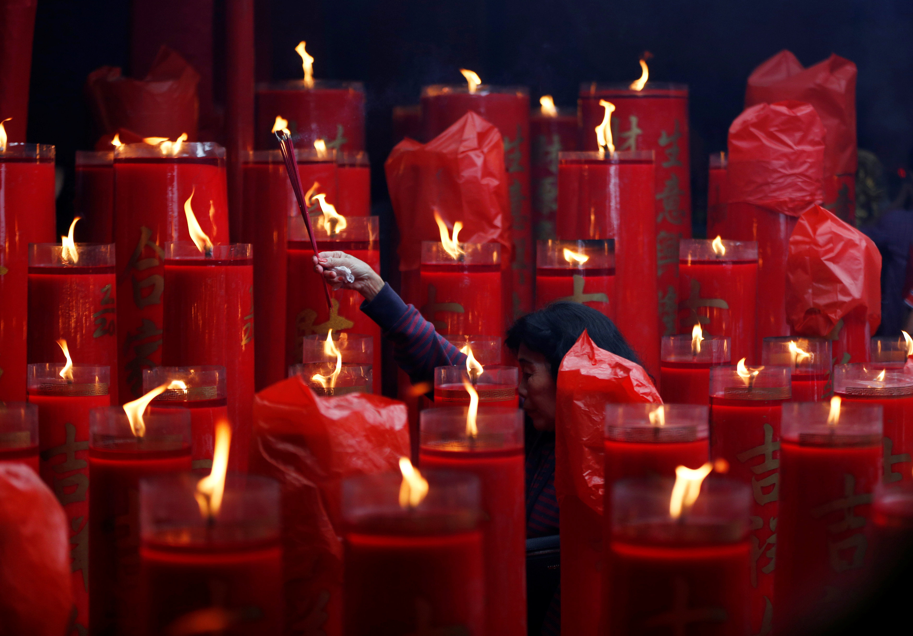 سيدة تشعل البخور والشموع داخل معبد فى اندونيسيا احتفالًا بالسنة القمرية الجديدة