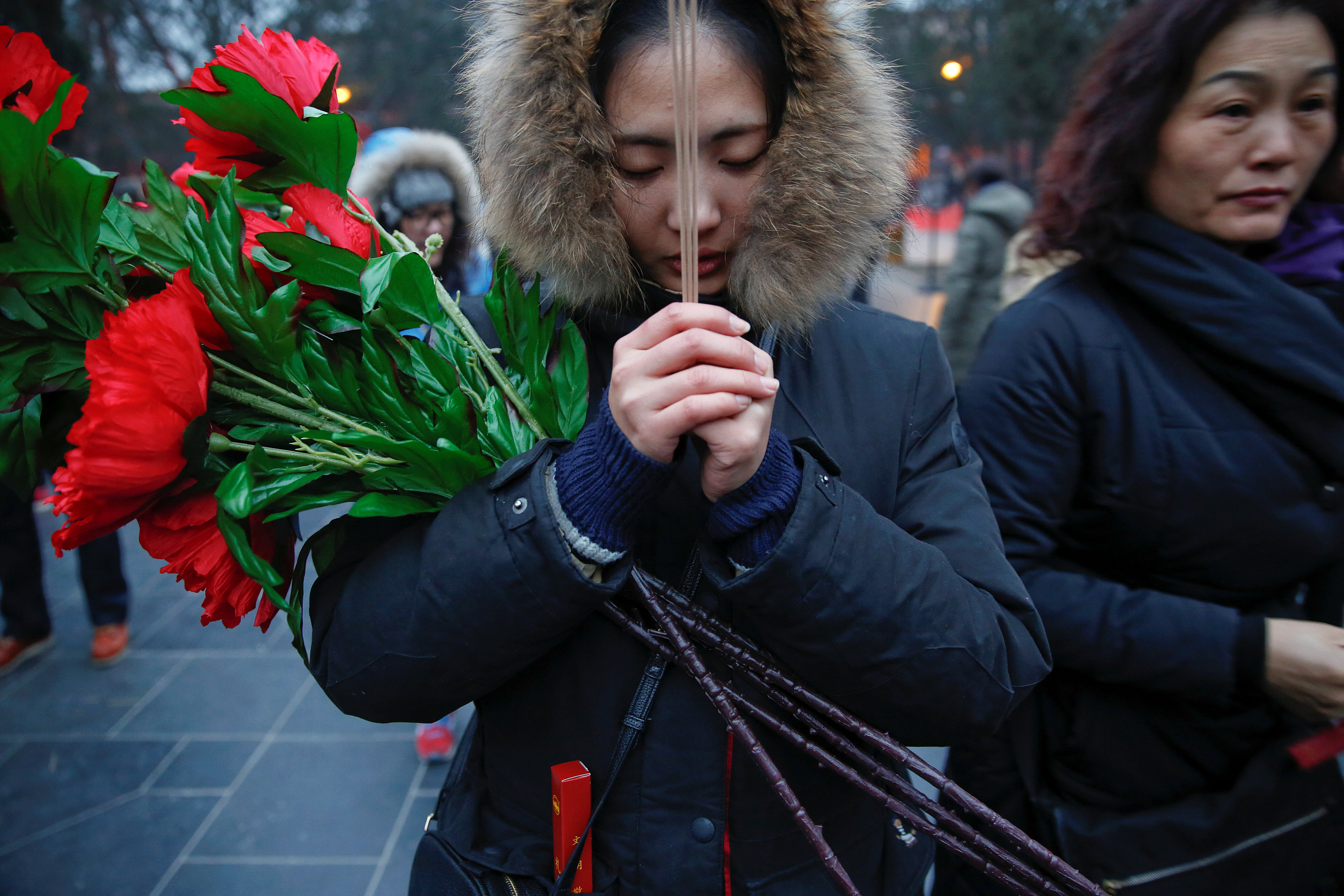 سيدة تحمل الورود والبخور خلال احتفالات السنة القمرية الجديدة فى الصين