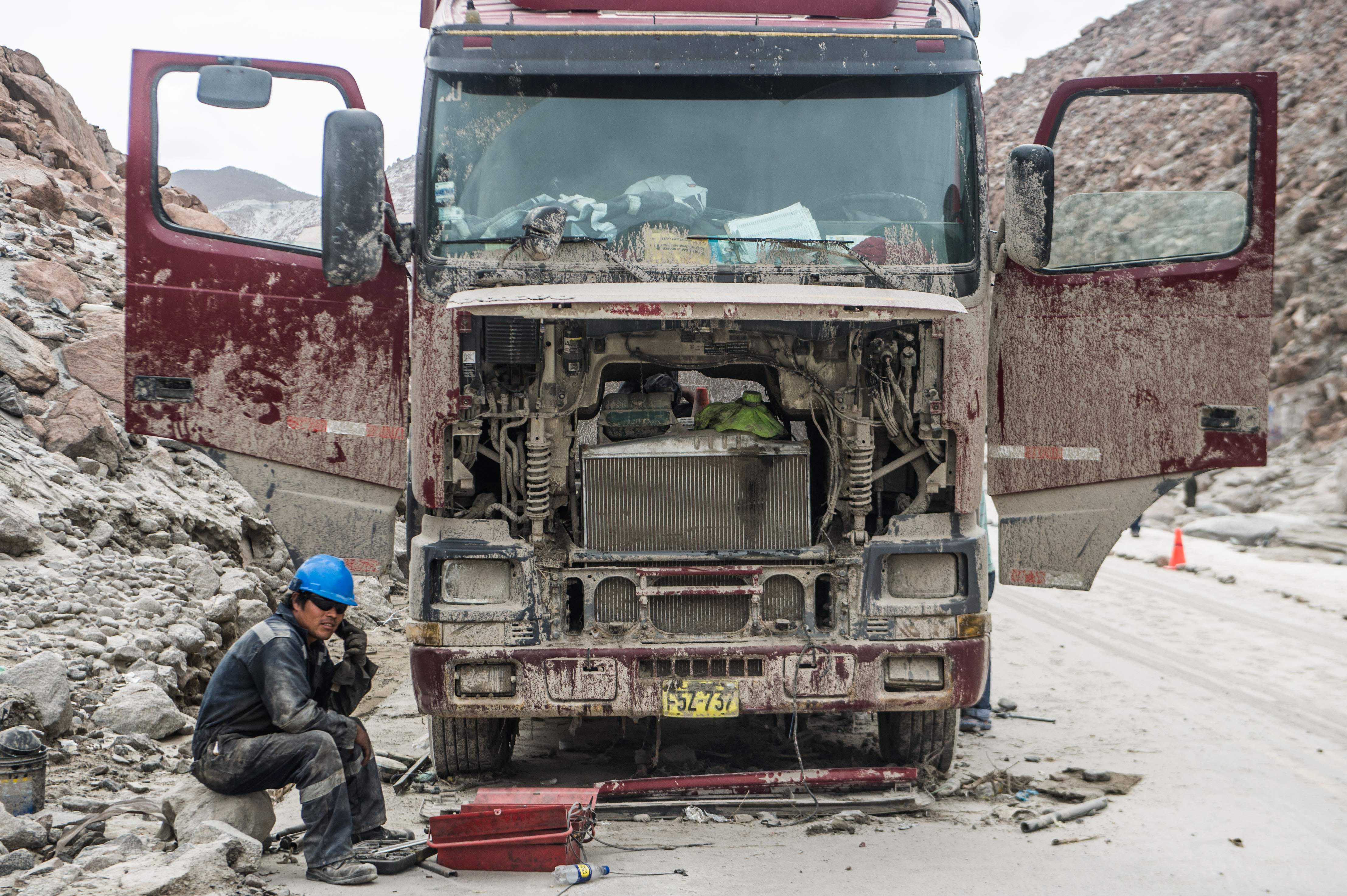 رجل يجلس بجوار شاحنة على طريق سريع فى بيرو بعد انهيار أرضى