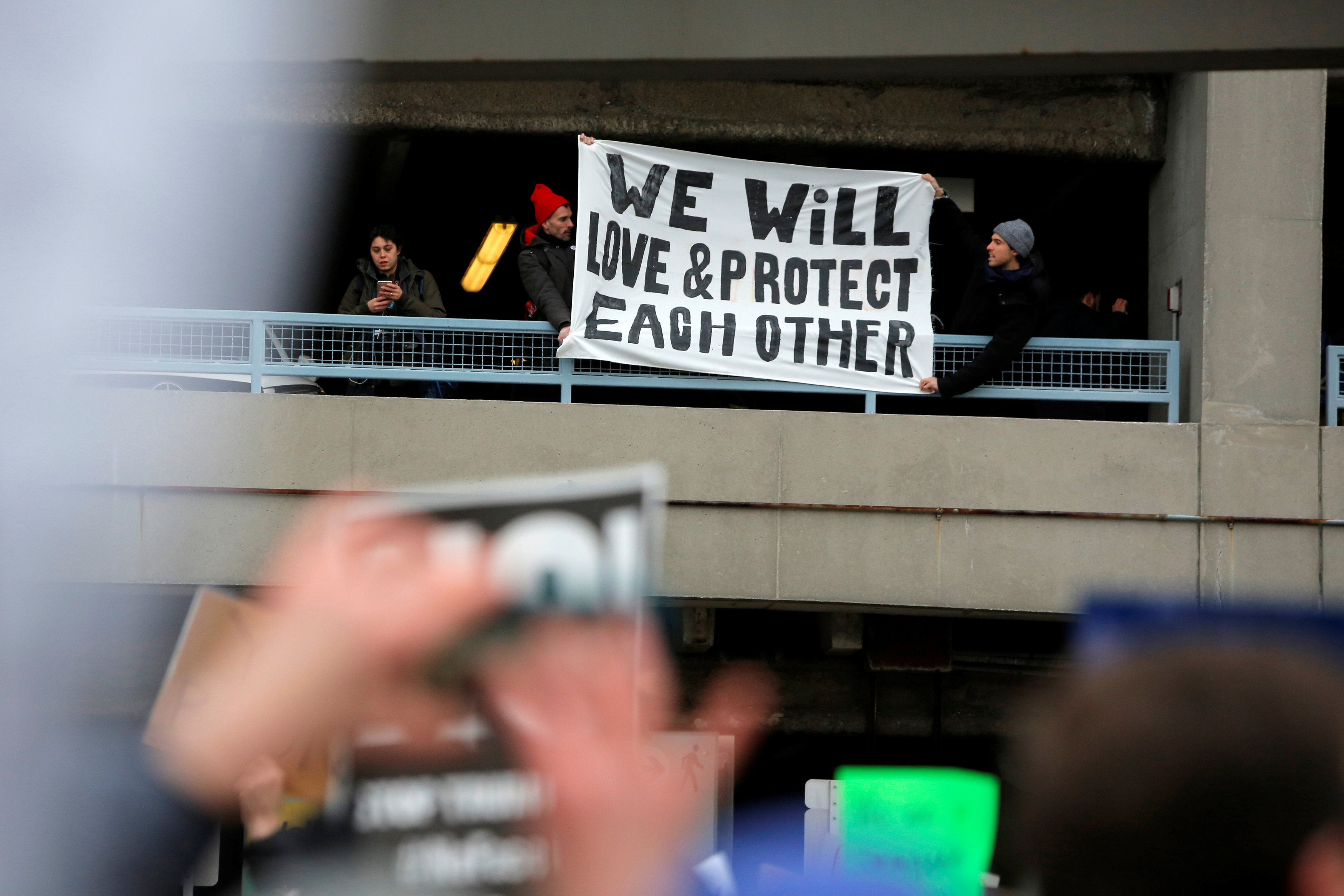المتظاهرون يرفعون لافتة خلال احتجاجات في مطار جون كينيدى الدولي ضد حظر ترامب دخول أمريكا
