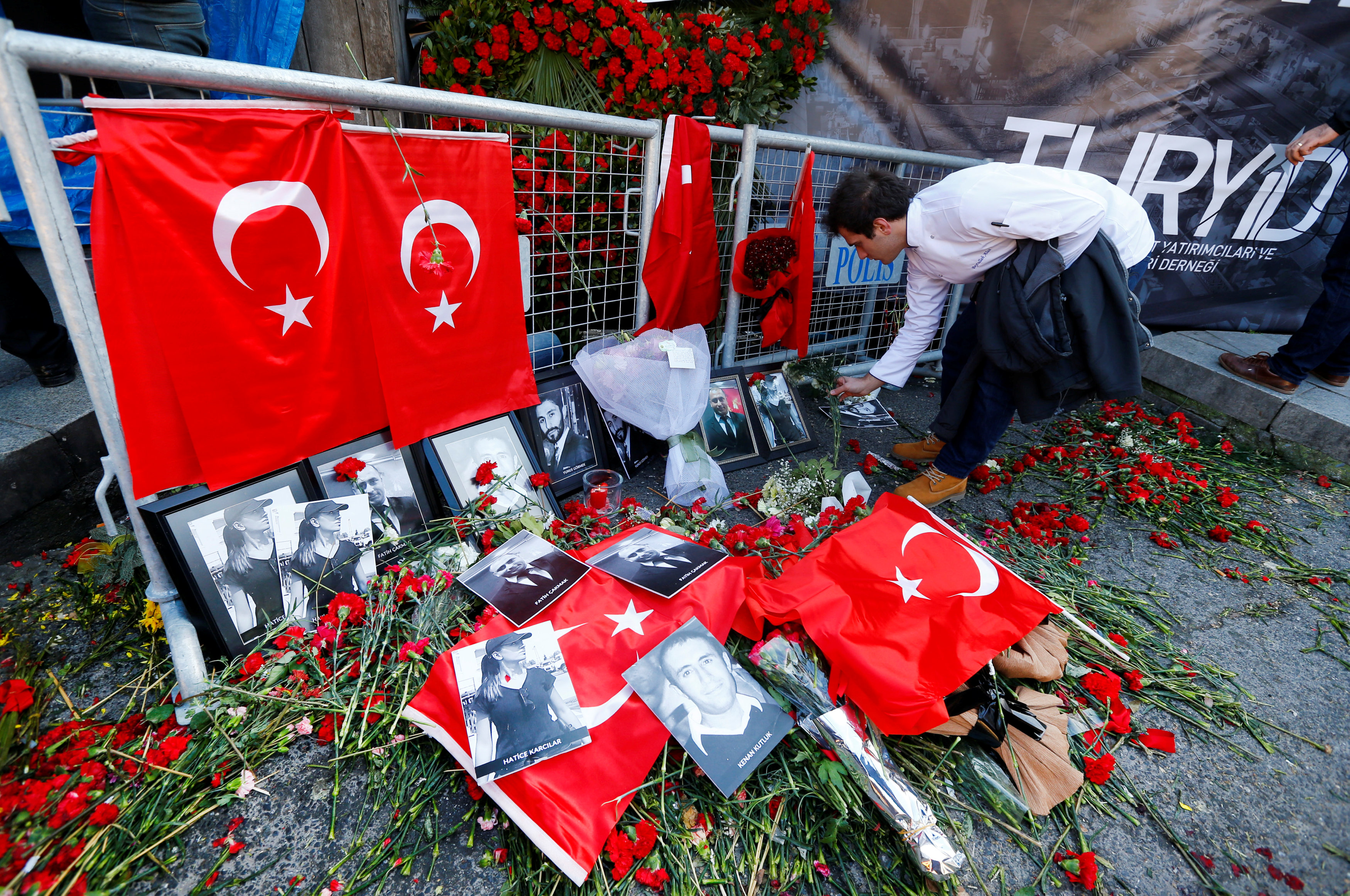 شخص يضع الورود أمام صور ضحايا الهجوم الإرهابى فى اسطنبول