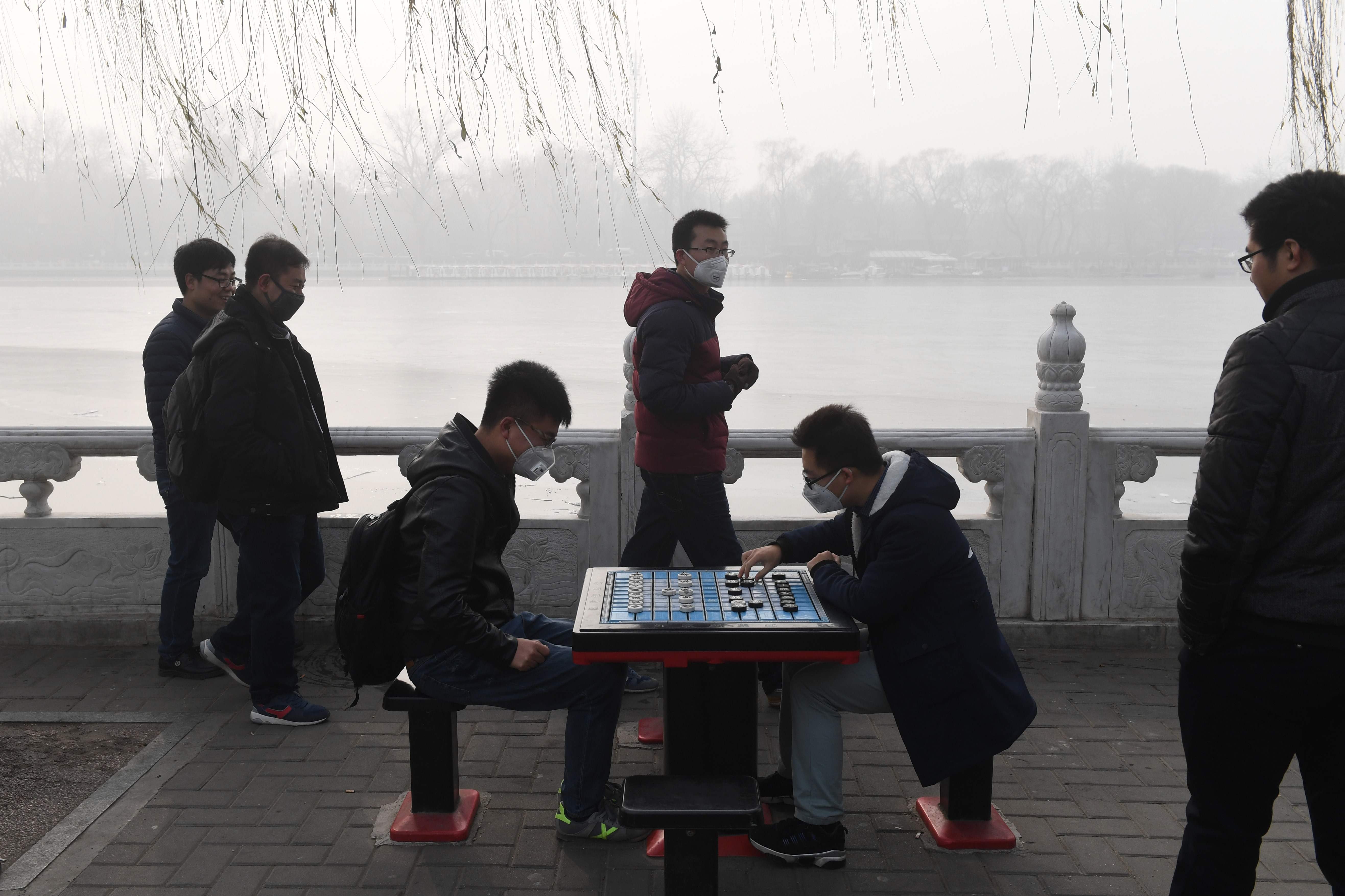 شابان صينيان يلعبان الدومينو فى الشارع رغم الضباب