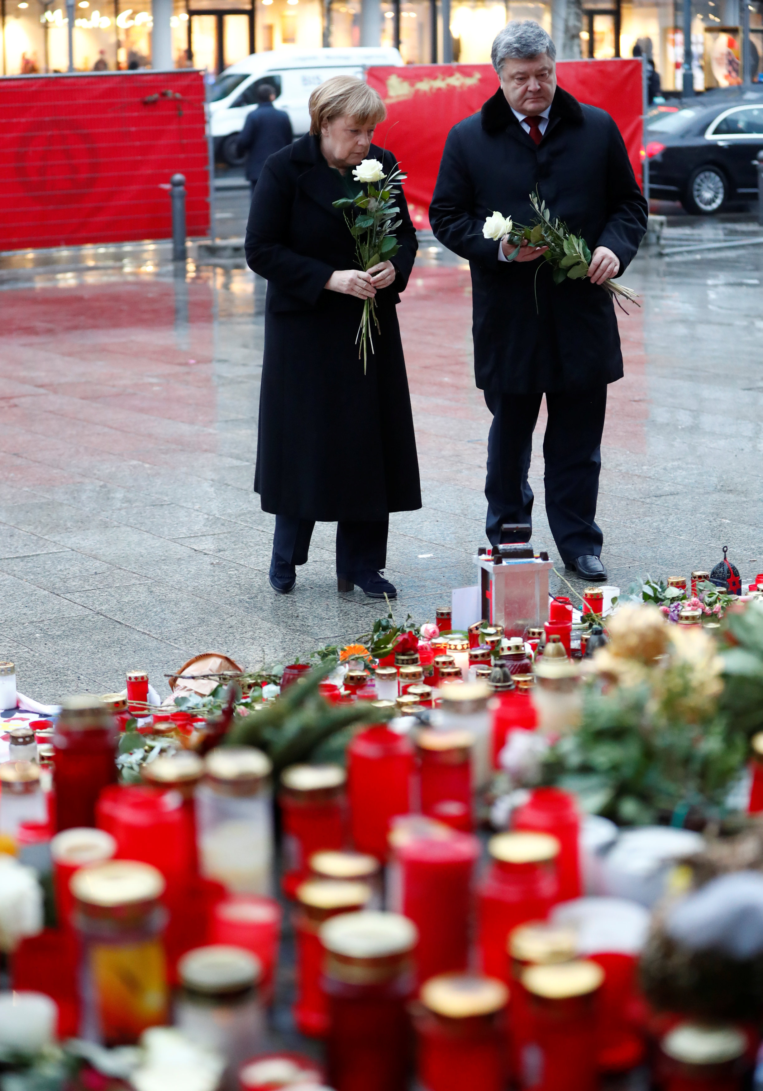 أنجيلا ميركل والرئيس الأوكرانى يحملان الورود أنثاء زيارتهما ساحة برلين