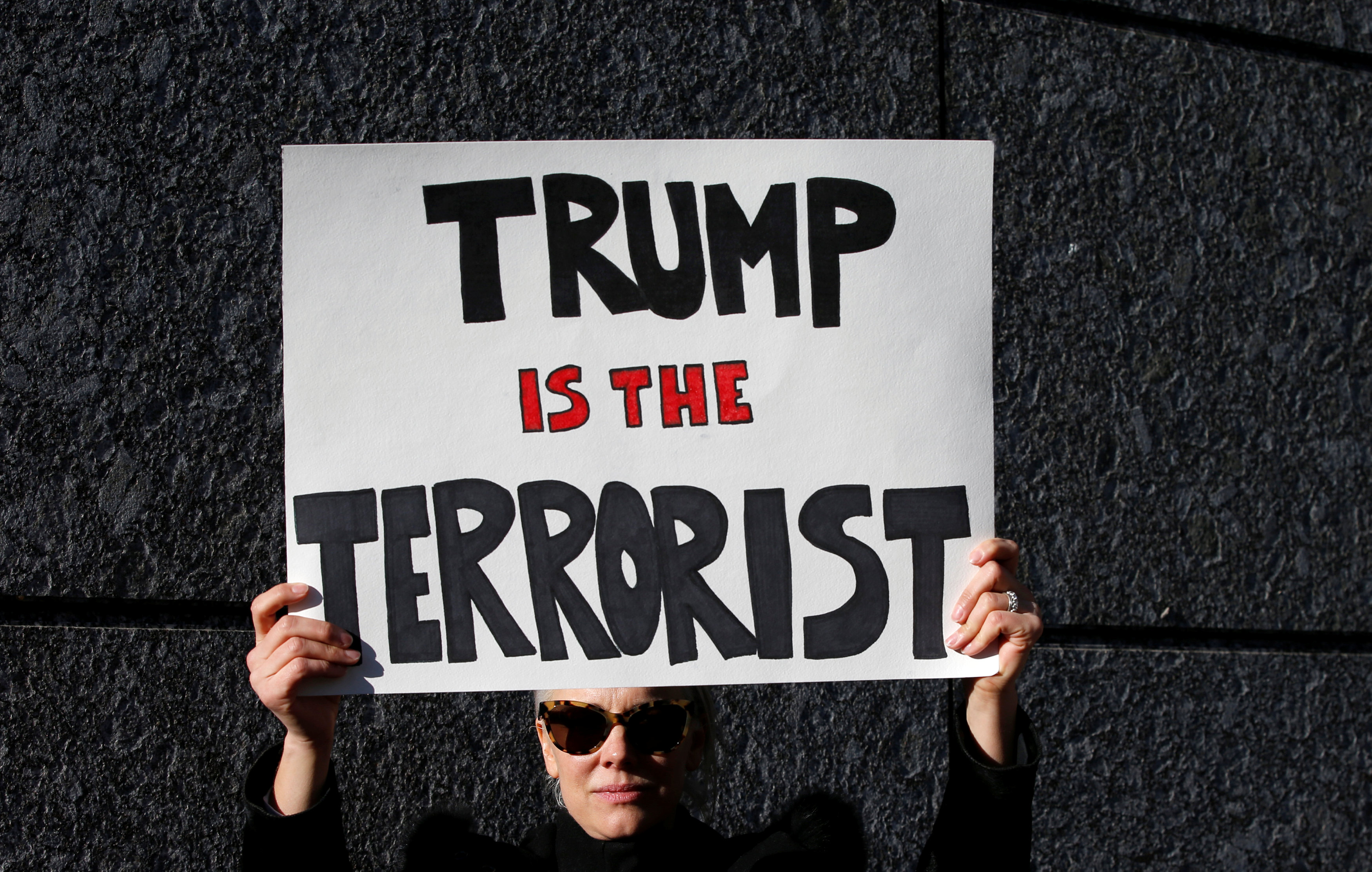 متظاهر أمام السفارة الأمريكية بطوكيو يرفع لافته مكتوب عليها ترامب هو الإرهابى