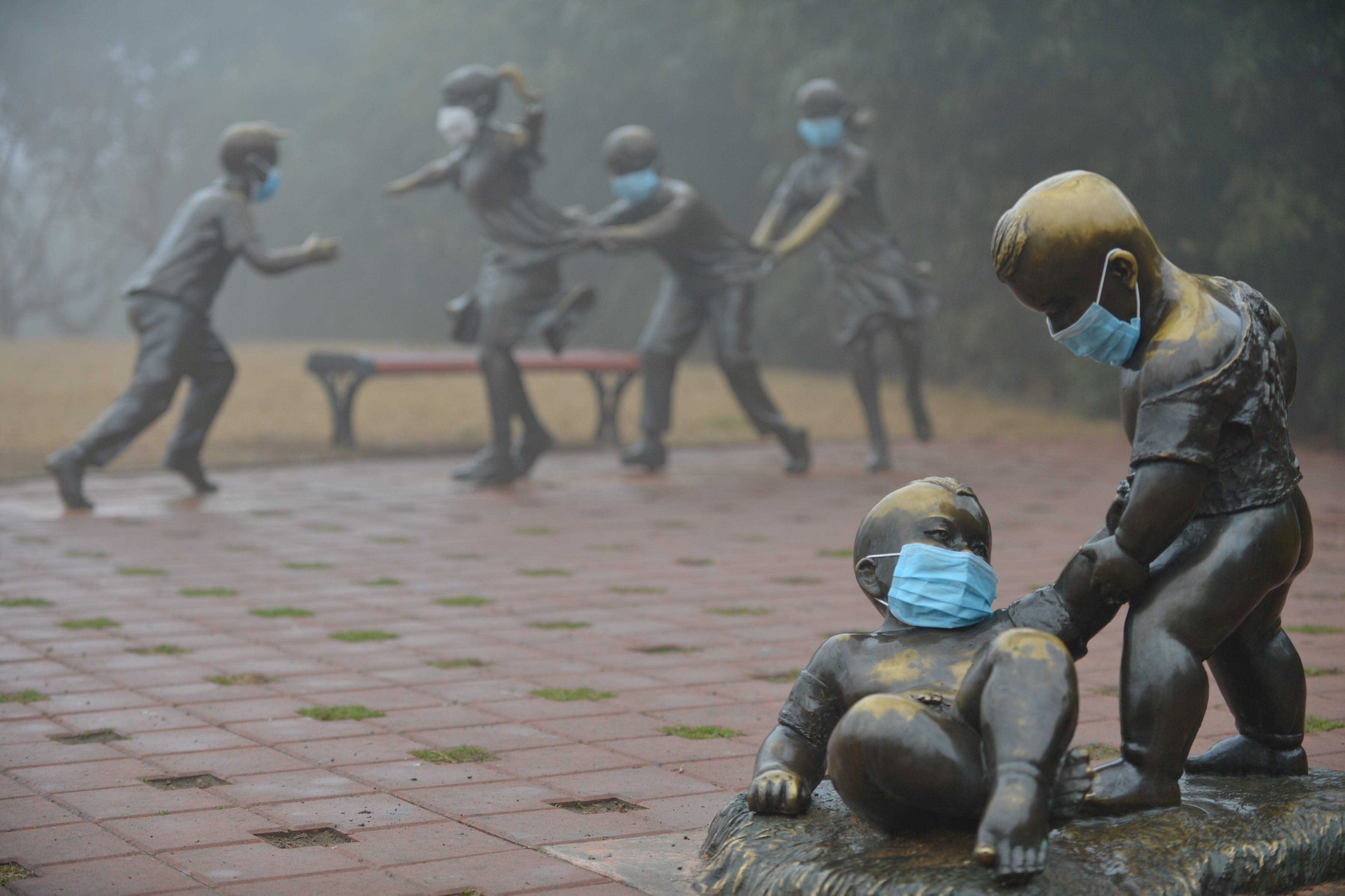 أقنعة على التماثيل في أحد الحدائق خلال يوم ضبابي في بويانغ