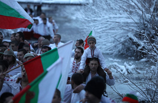 مواطنون يحملون أعلام بلغاريا أثناء الاحتفال بعيد الغطاس
