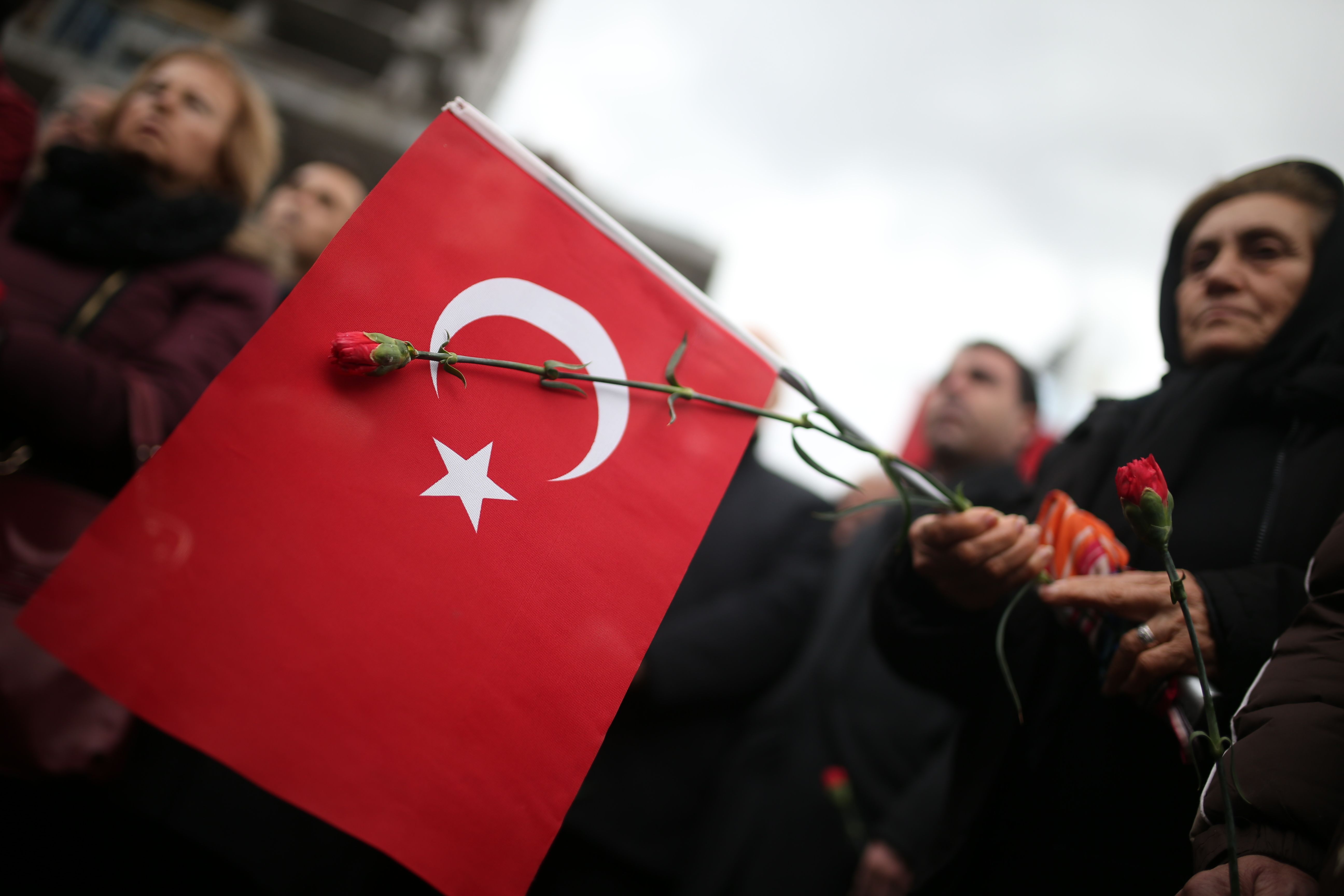 سيدة تحمل علم تركيا ووردة فى جنازة قتلى إزمير