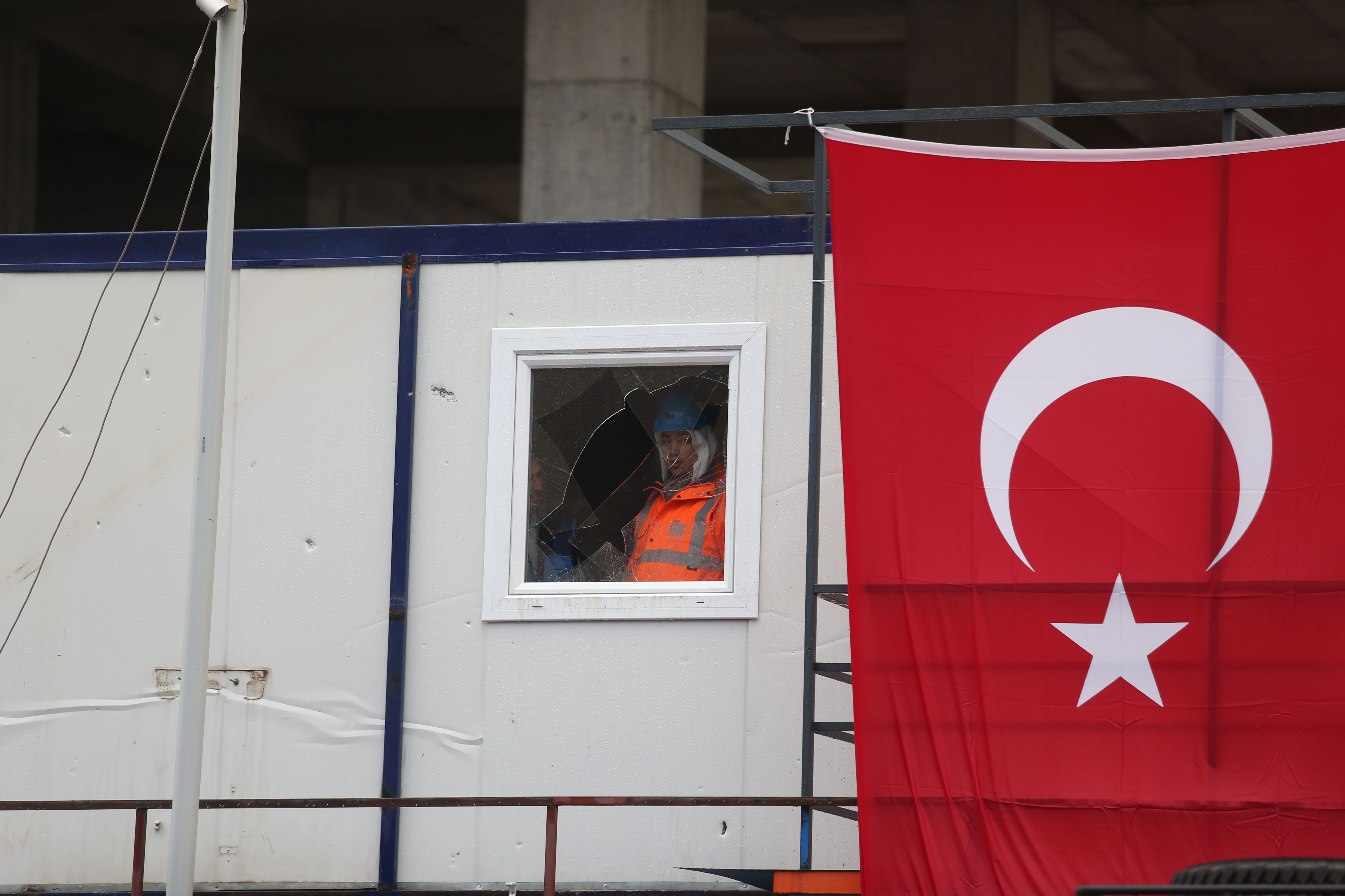 عامل يقف خلف نافذة محطمة بأحد الأكشاك فى منطقة الإنفجار بإزمير التركية