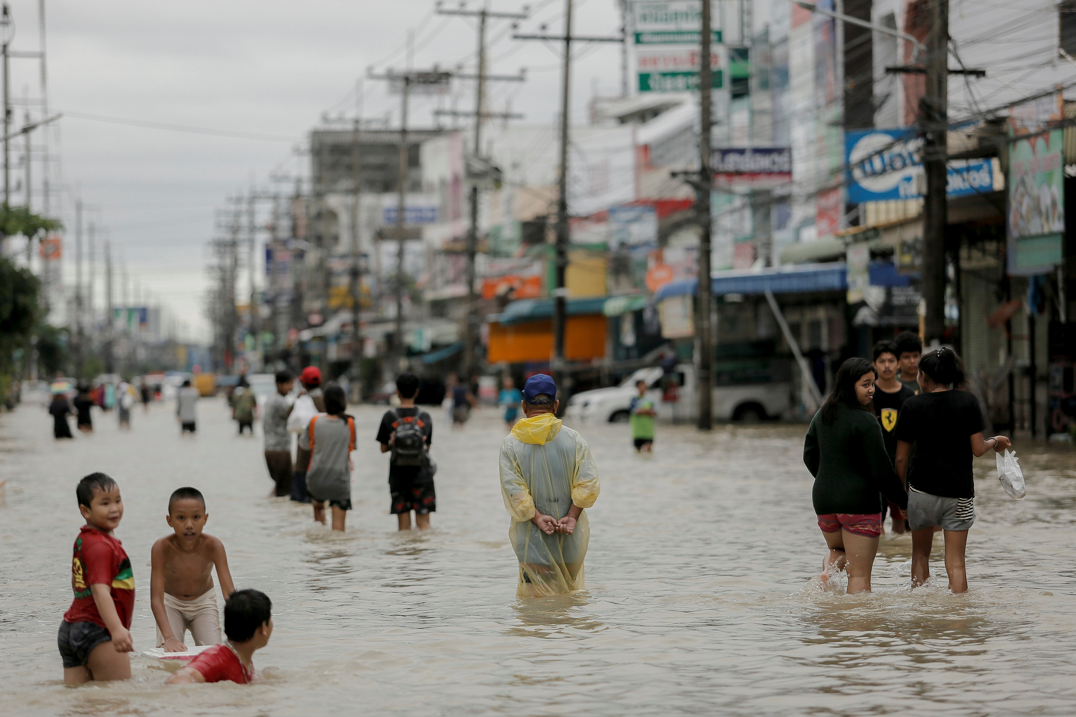 أطفال يلهون ومارة يسلكون فى مياه الفيضانات بشواع تايلاند - رويترز