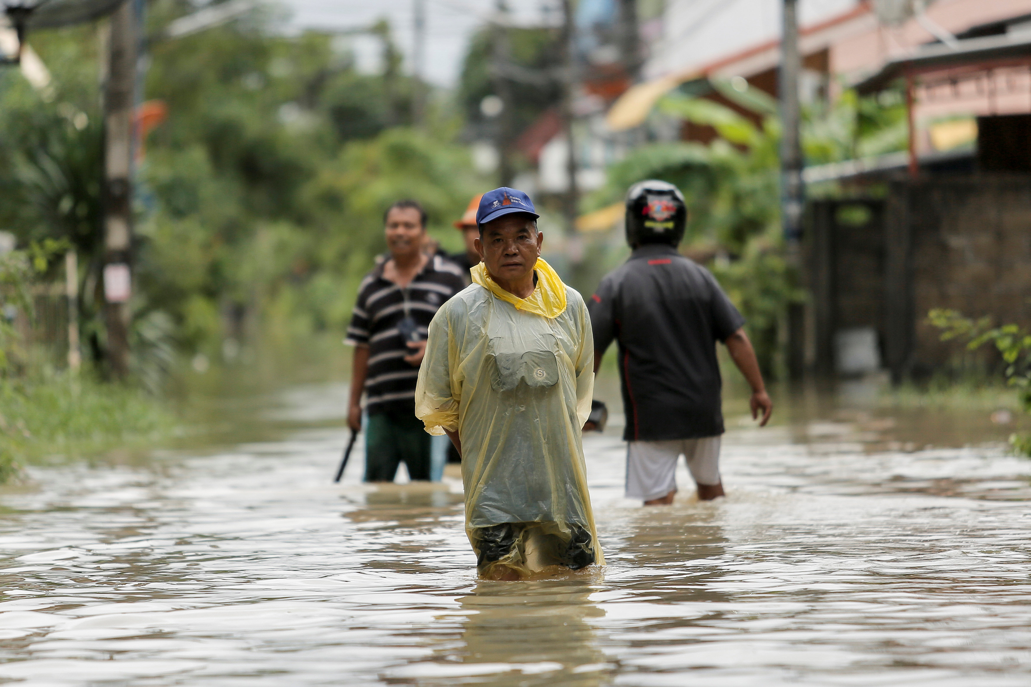 سكان يمشون فى مياه الفيضانات بشواع مقاطعة موانج فى تايالند - رويترز