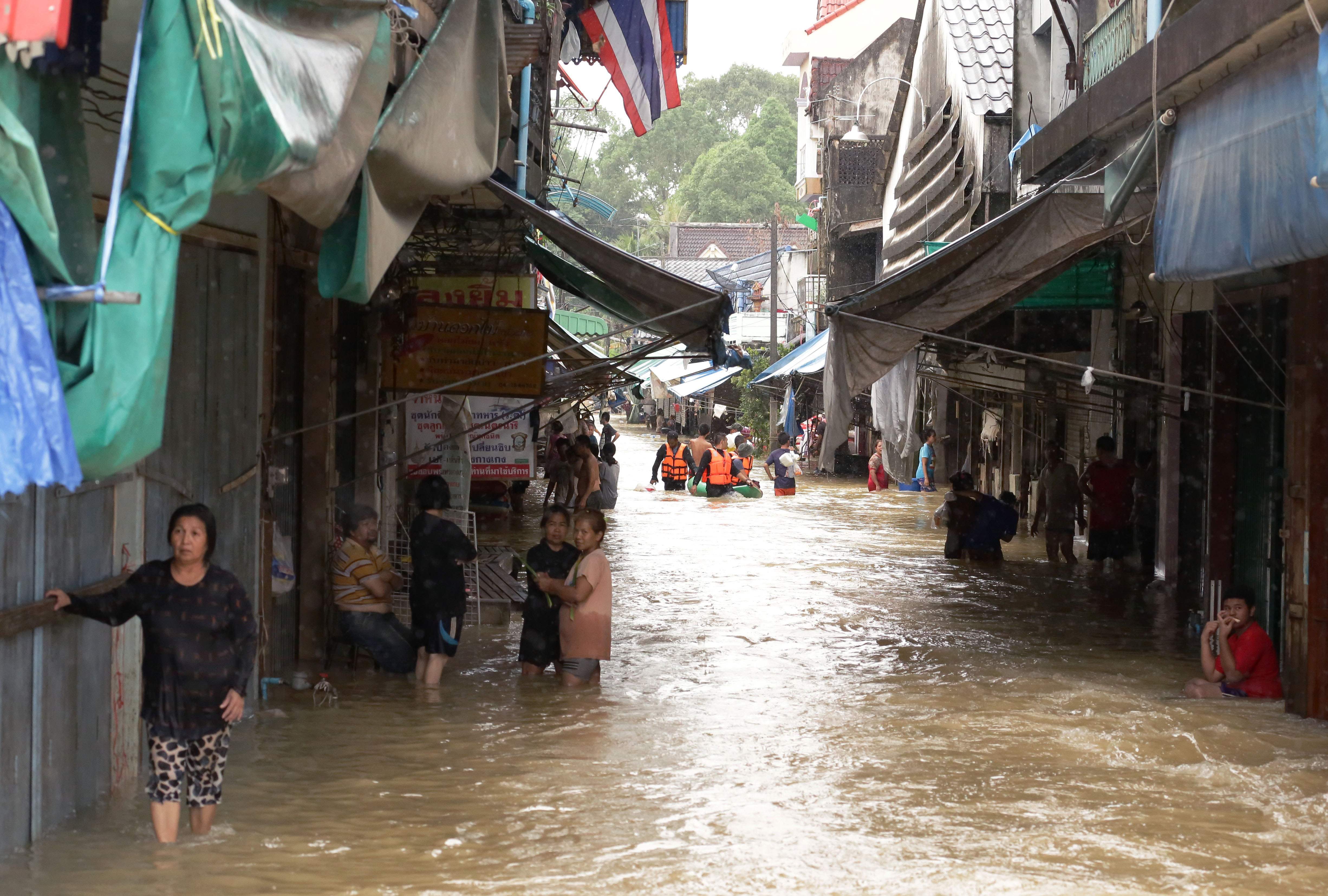 سكان فى إحدى القرى فى تايلاند خارج يقفون خارج منازلهم بسبب فيضانات مياه الأمطار - أ ف ب