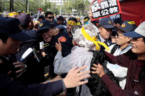 متظاهر يجذب أحد أفراد الشرطة فى تايوان من وجهه