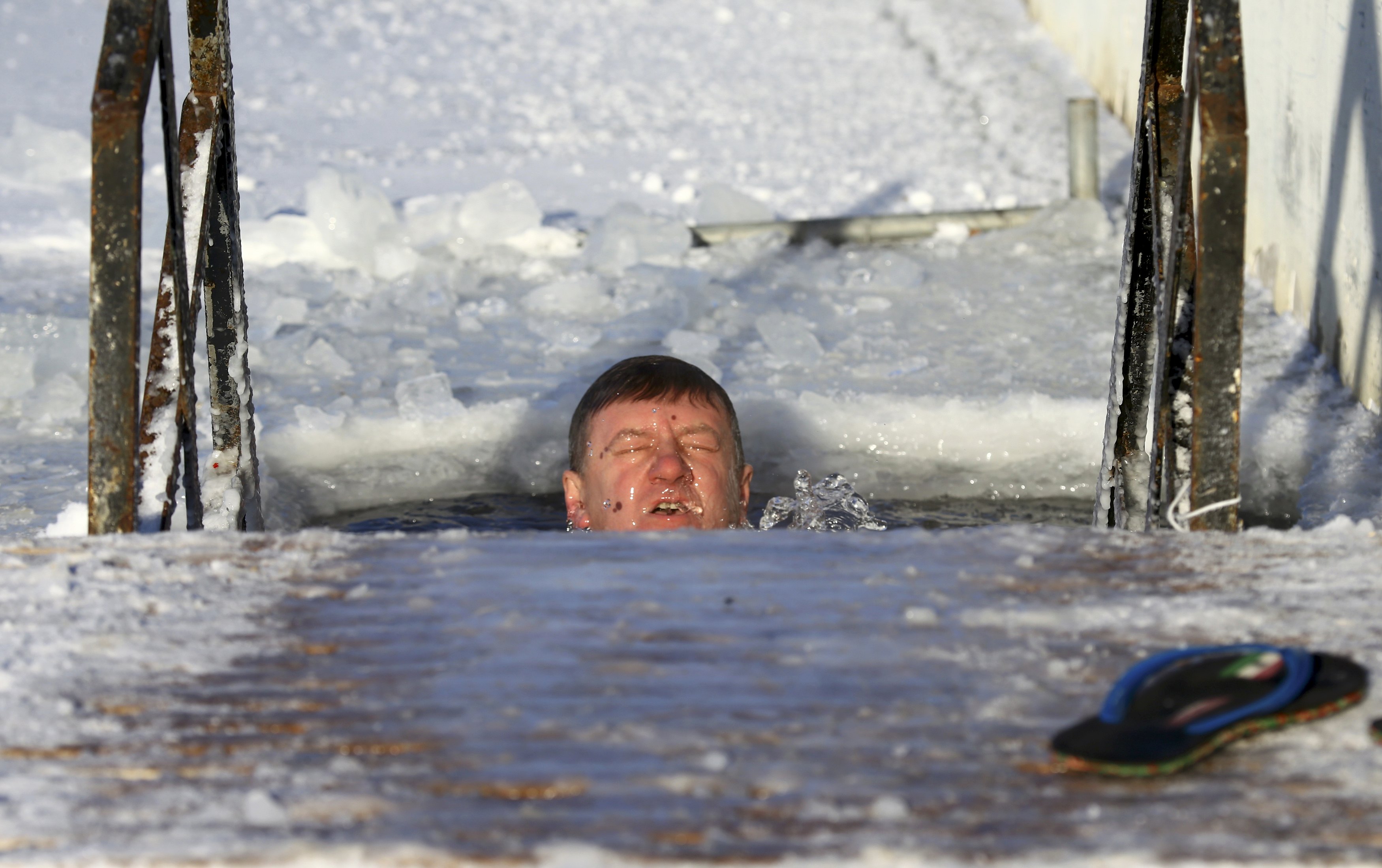 رجل وسط المياه الجليدية بعد تراجع دراجات الحرارة بعاصمة روسيا البيطاء