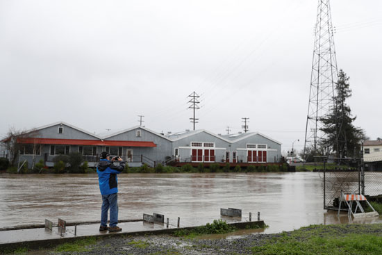 رجل يلتقط صورة لمياه الفيضان فى شوارع مدينة بيتالوما الأمريكية