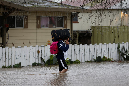 شاب يسير وسط مياه الفيضان بشوارع بيتالوما فى أمريكا