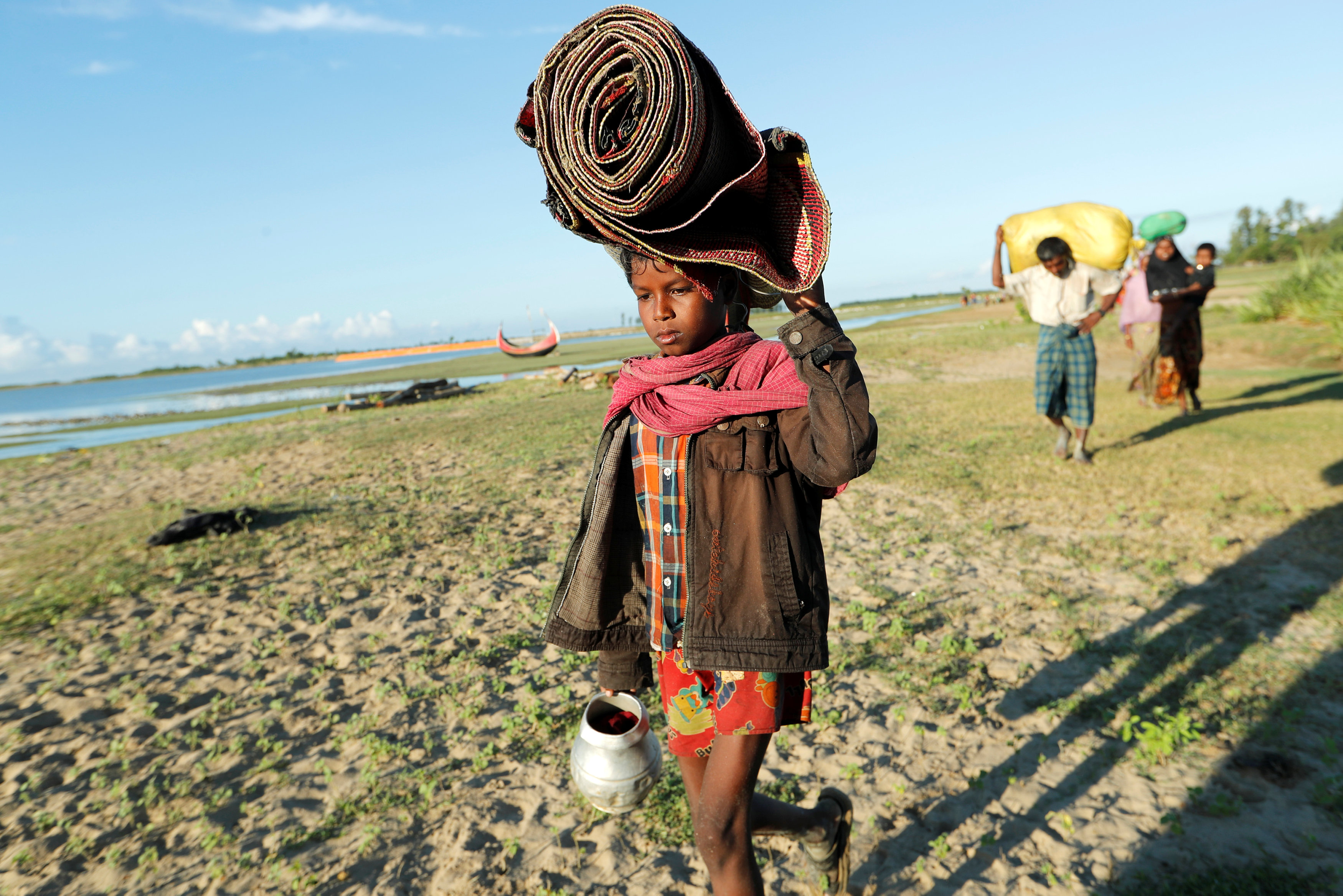 طفل يحمل مقتنيات اسرته خلال هروبهم من الموت فى ميانمار