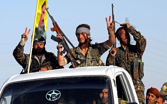 مقاتل بسوريا الديمقراطية يرفعون علامة النصر أثناء دخولهم الرقة