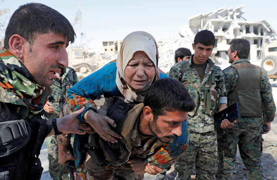 مقاتل بسوريا الديمقراطية يحمل سيدة عجوز على ظهره